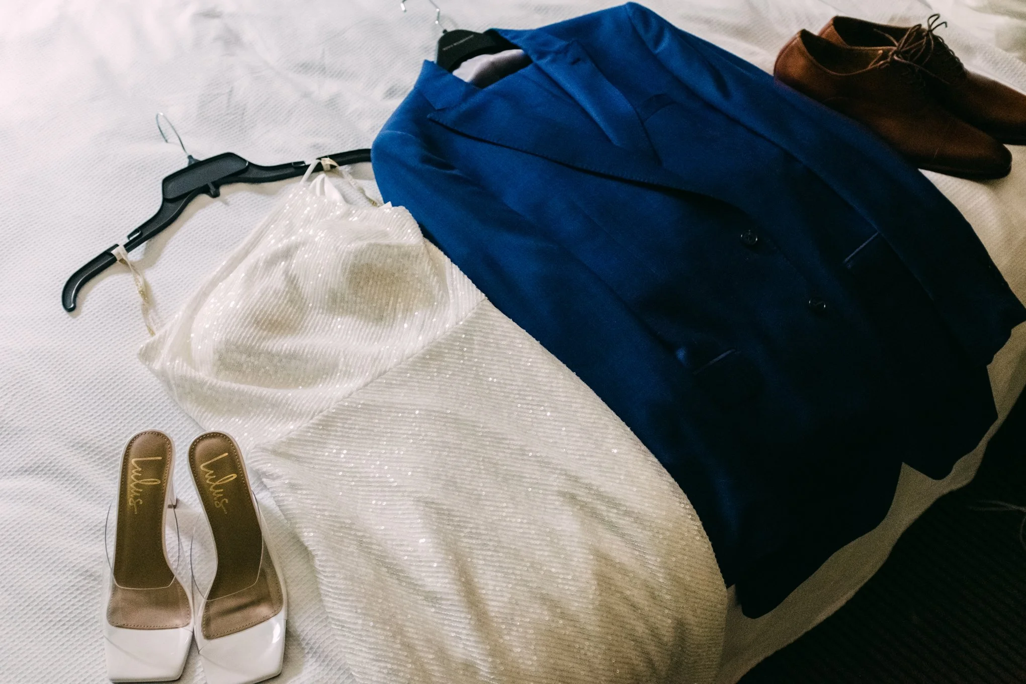 A neatly arranged outfit including a blue blazer, a white sequin top, beige high-heeled shoes with 