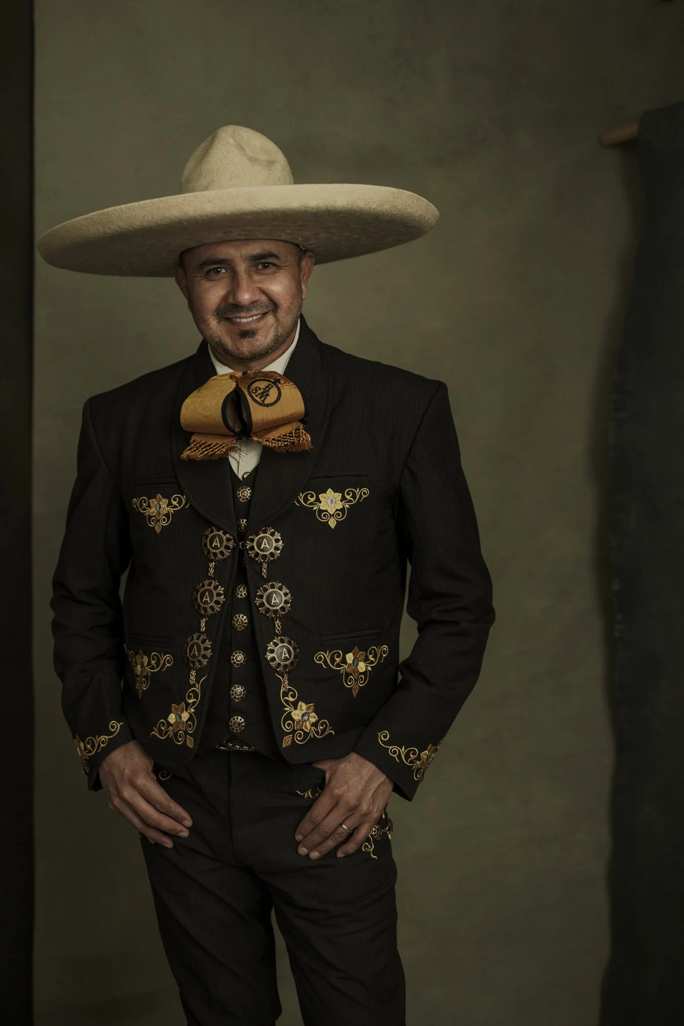 Man dressed in traditional Mexican charro suit with a wide-brimmed sombrero, smiling at the camera.