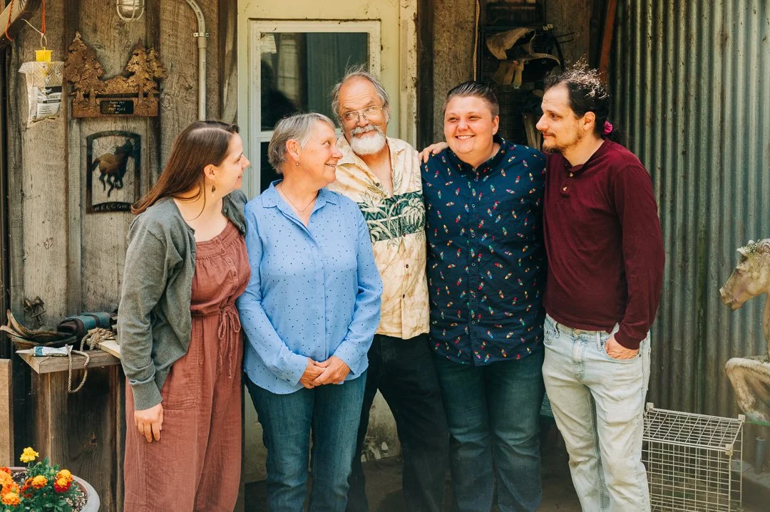 Six people standing together outside a rustic building, smiling and posing for a photo.