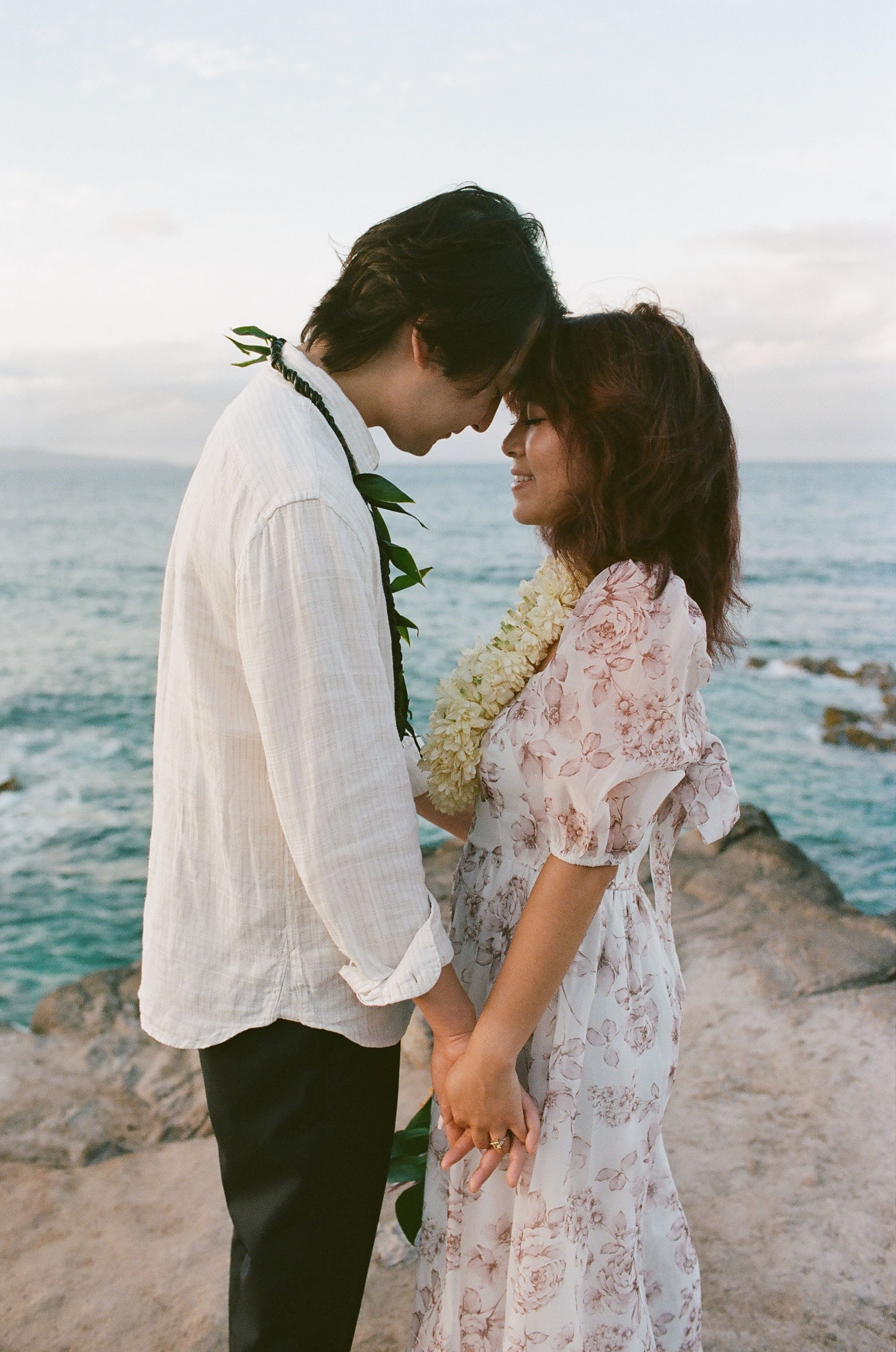 Surprise engagement photography in Maui, Hawaii with tropical floral leis and just engaged couple photographed on digital and film photography by Maui based wedding photographer, Lesley Castle Photo.