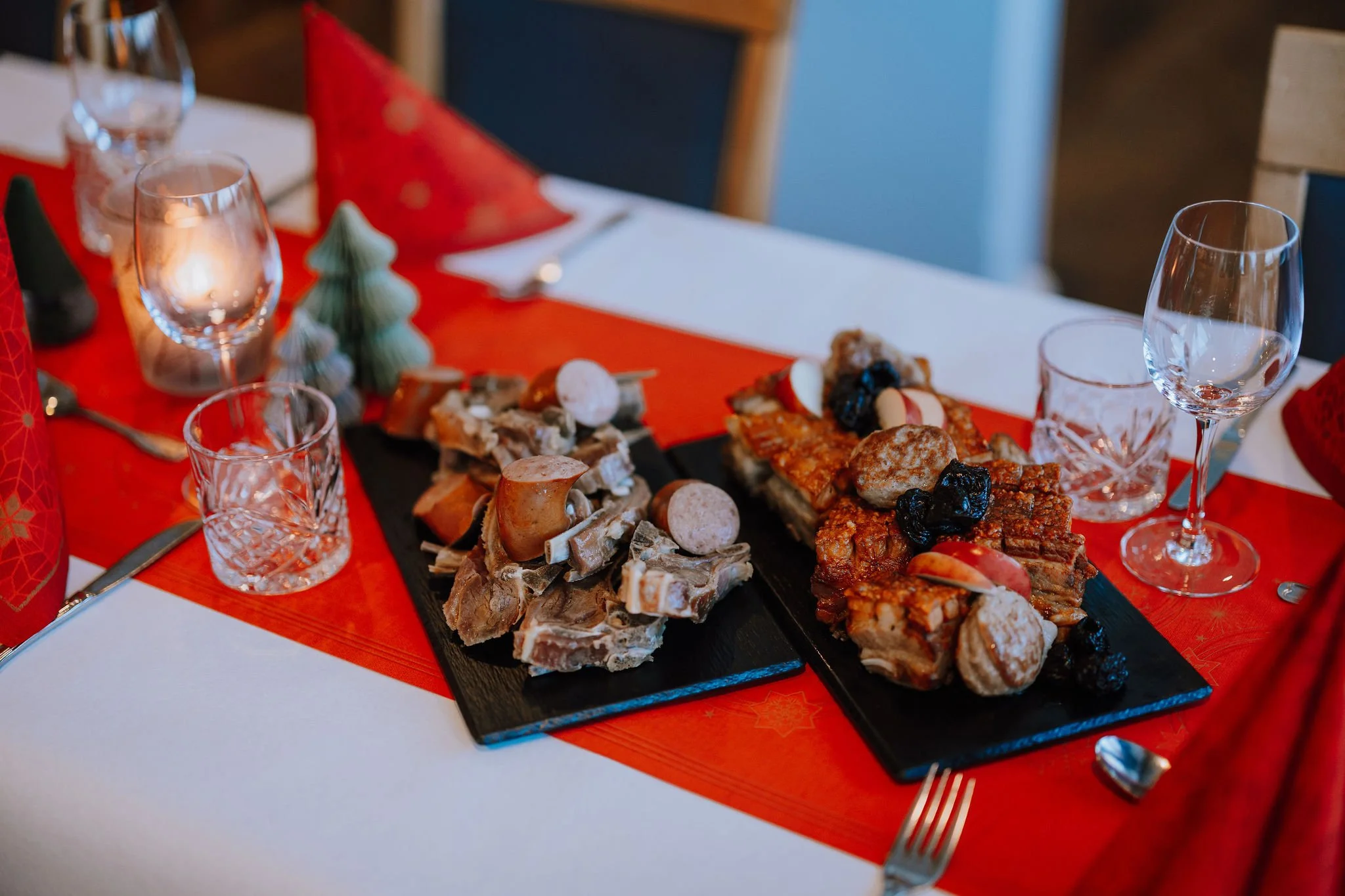 Foto viser julemat på et pent dekket bord med rød duk og grønne dekor juletrær.