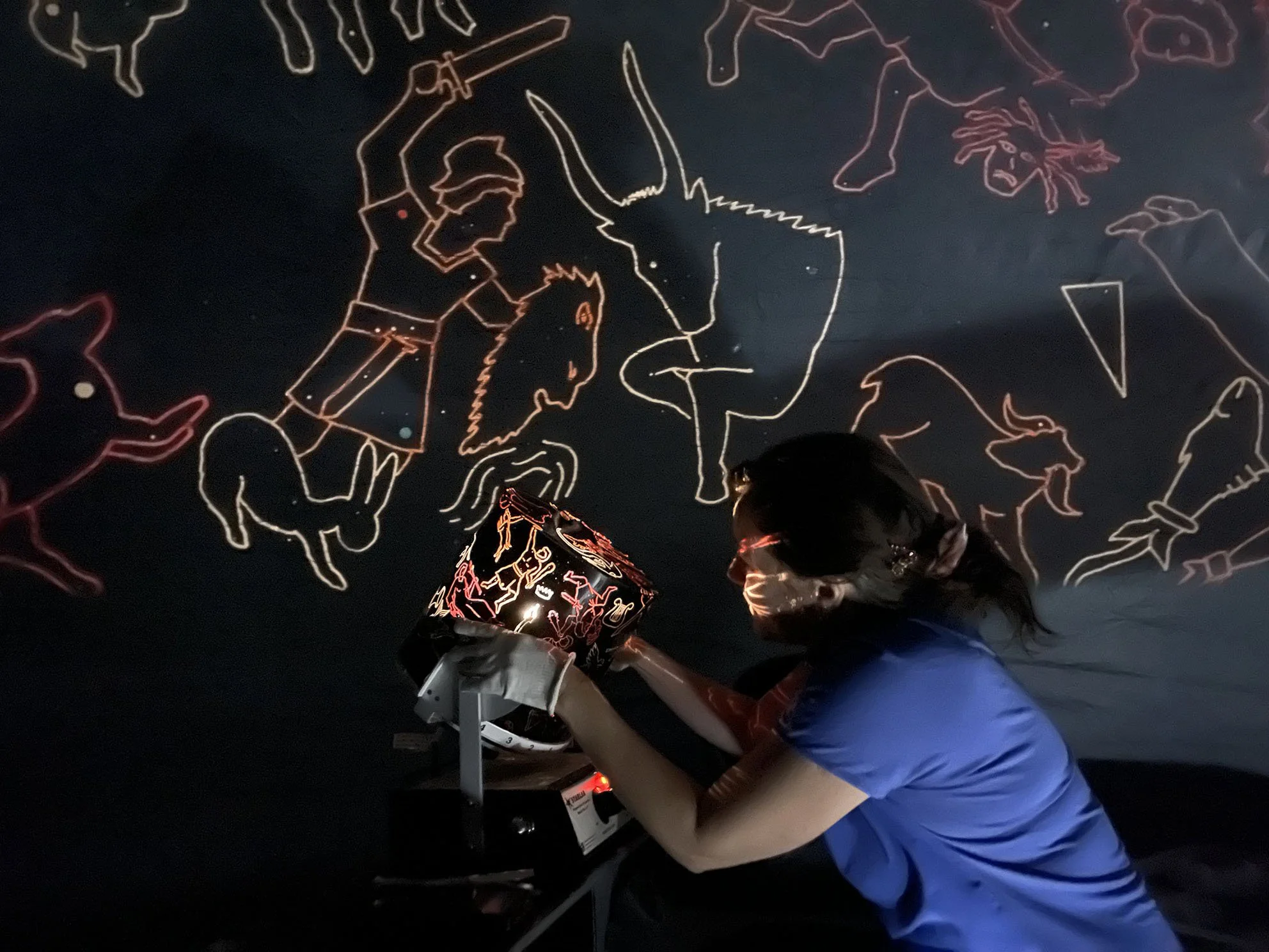 Foto viser museumspedagogen som viser betjener maskinen som viser stjernebilder inne i museet oppblåsbare stjernetelt.