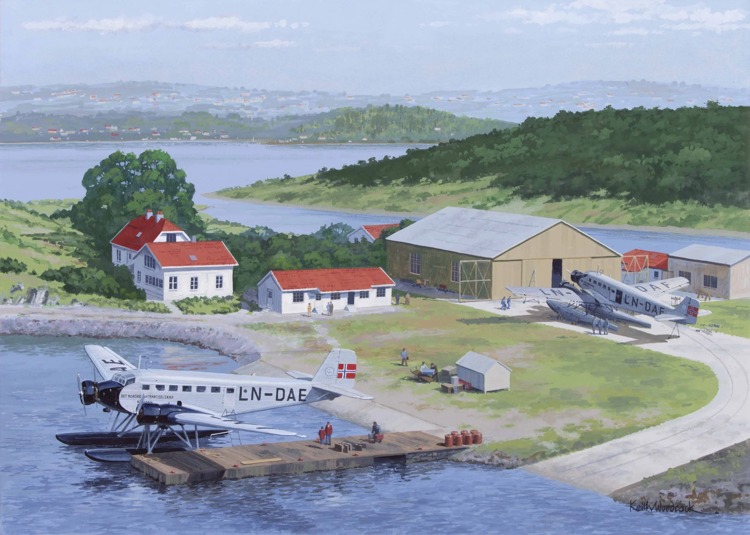 Bildet viser sjøflyet Junkers 52 liggende ved en kai. Personer står på kaia med bagasje klar til å reise. Det ligger hus og en driftsbygning på gården.