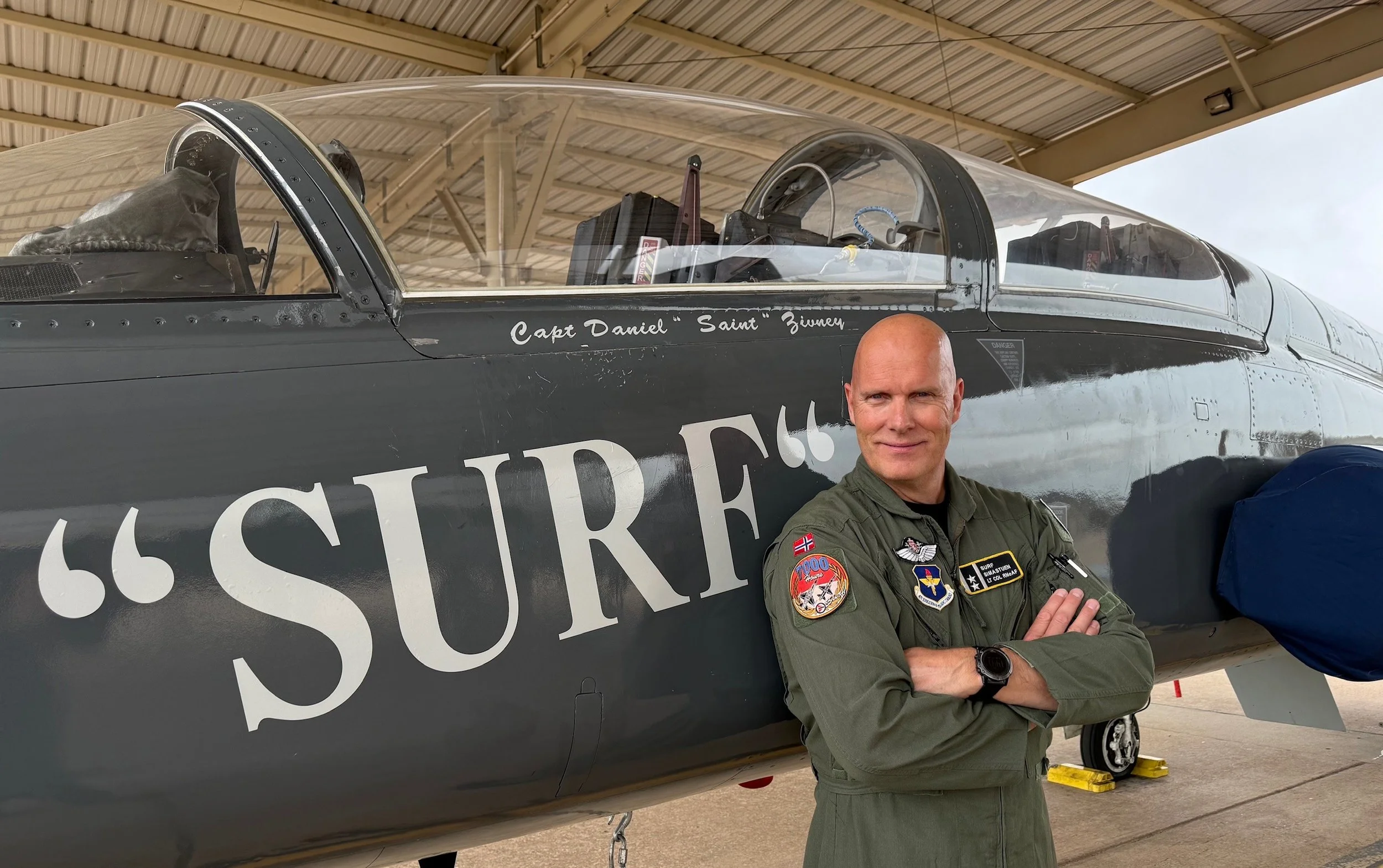 Foto viser F-16 f pilot Dag Simastuen foran et F-16 fly. Hans kallenavn SURF står med store bokstaver på flysiden.