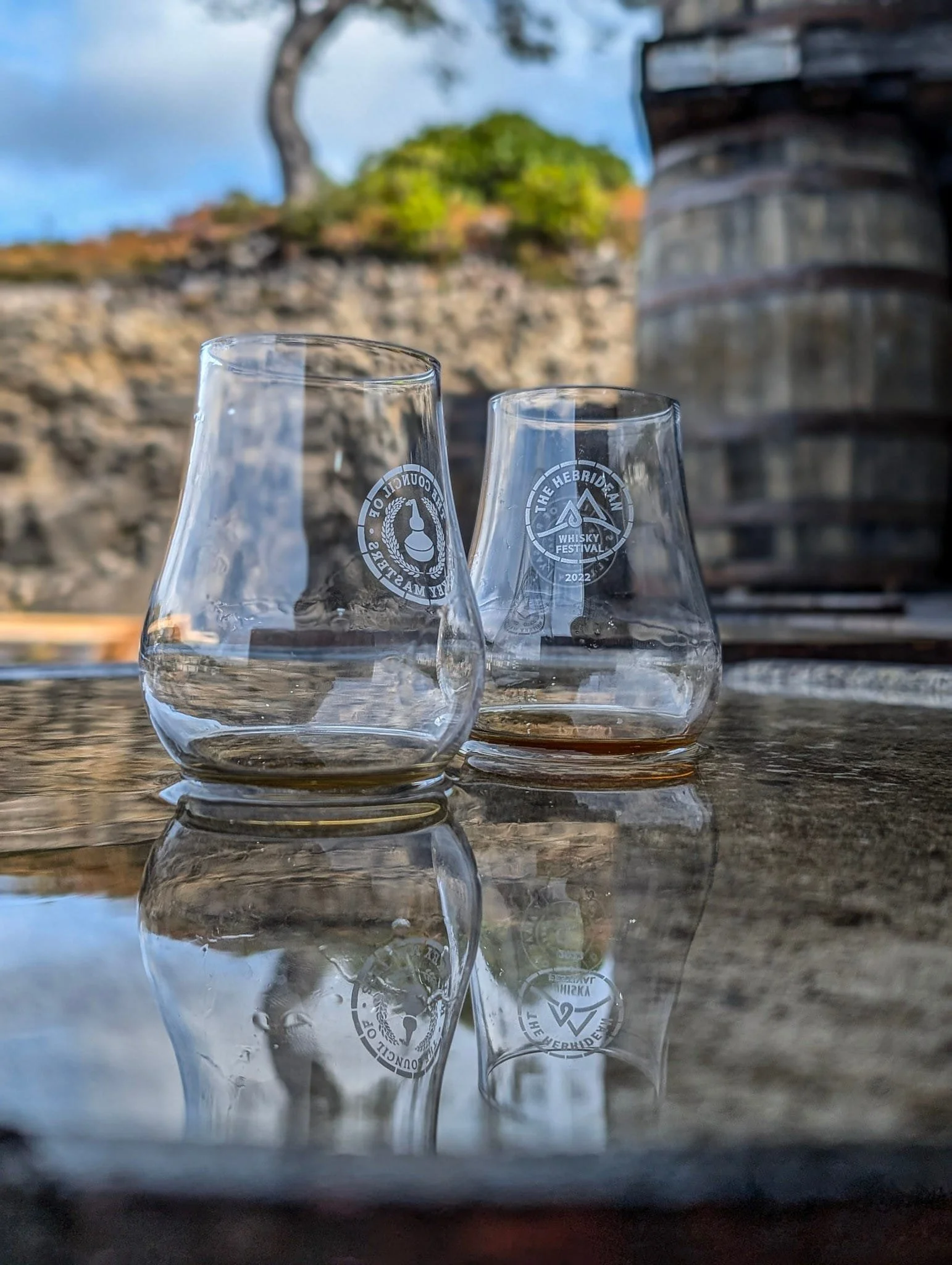 Two glencairn whisky glasses reflected in a barrel