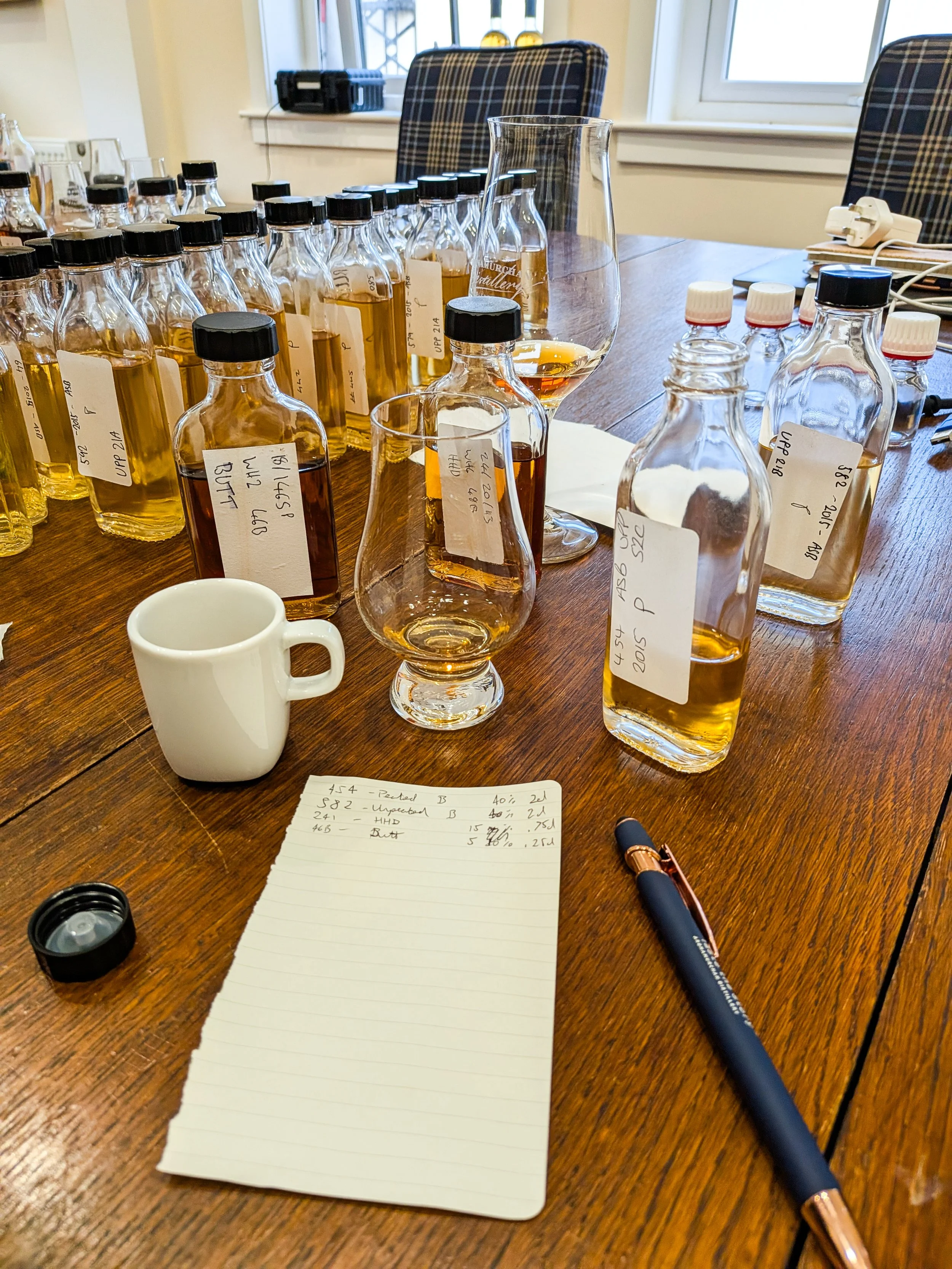 A pen and paper in front of a group of whisky blending bottles