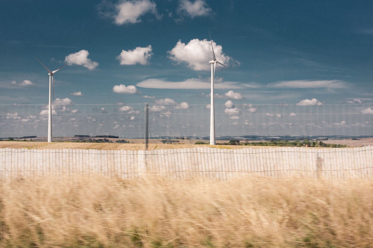 Champ de blé avec des éoliennes sous un ciel bleu avec des nuages.