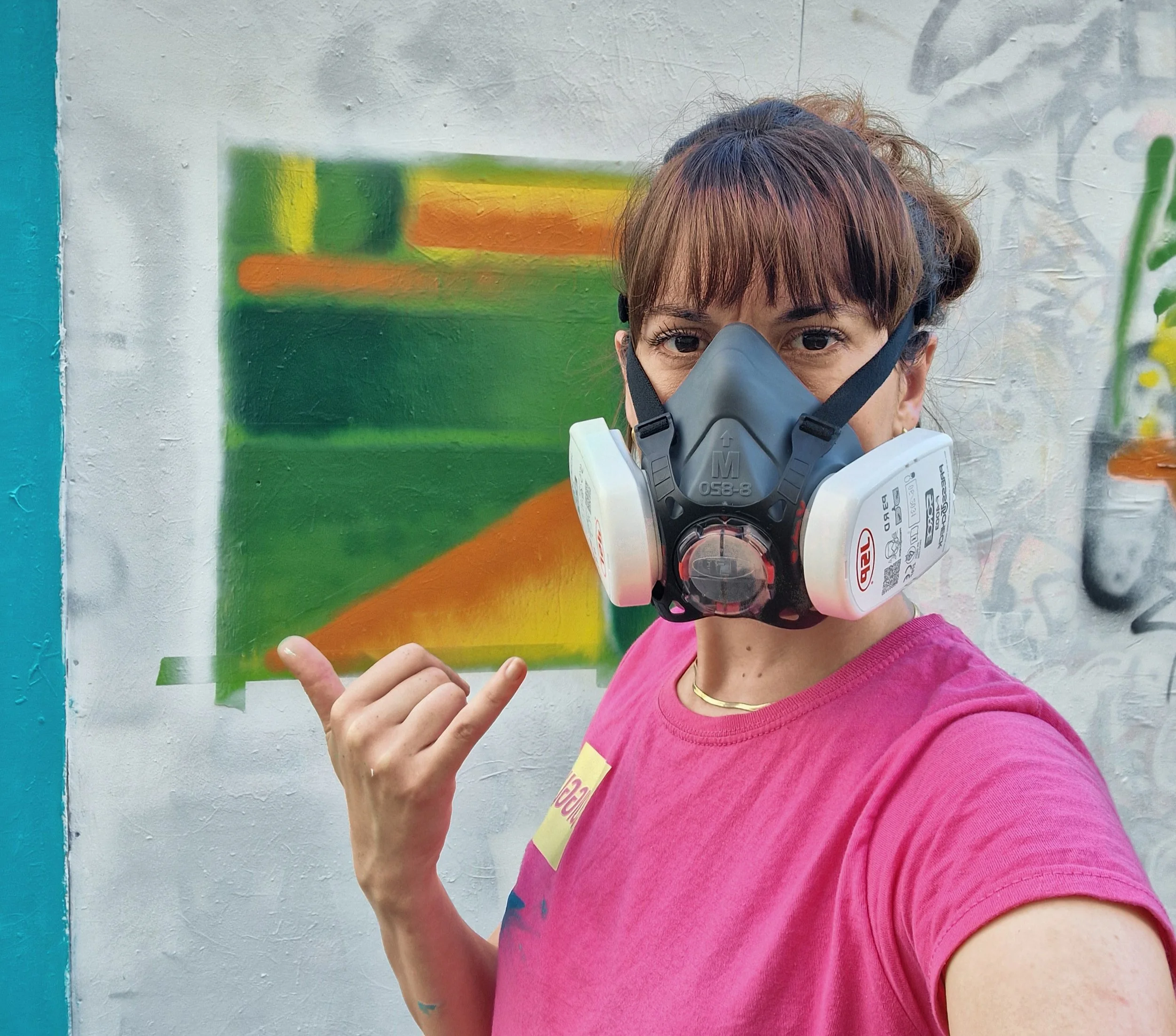 female artist wearing a face mask using spray paint