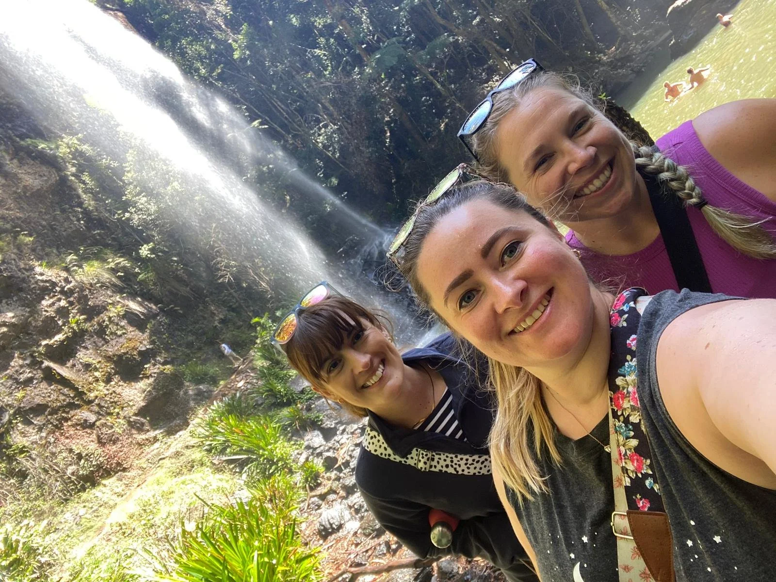 three artists stood in in front of a stunning waterfall in Australia after going for a long hike
