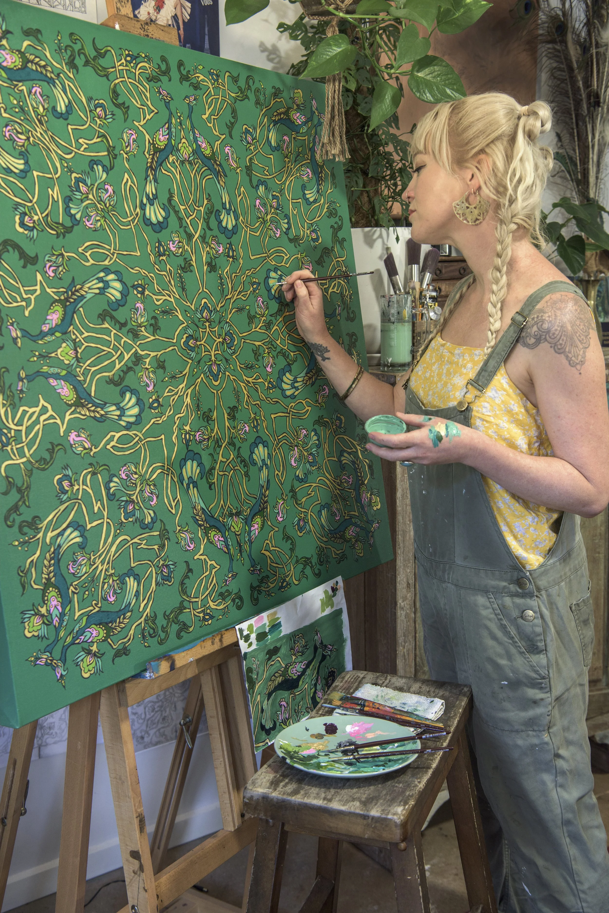 Artist Elizabeth Gleeson stood painting at an easel with a paint brush in hand