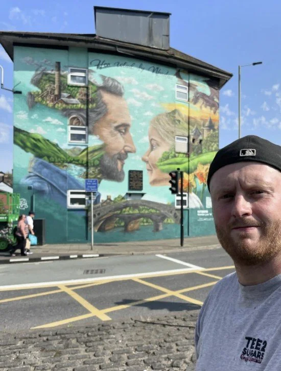 artist Tee2Sugars taking a selfie infront of one of his own murals in wales