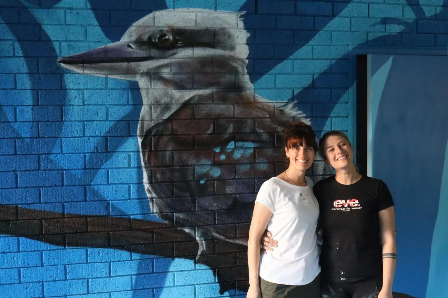 two artists stood in front of a giant kookaburra mural