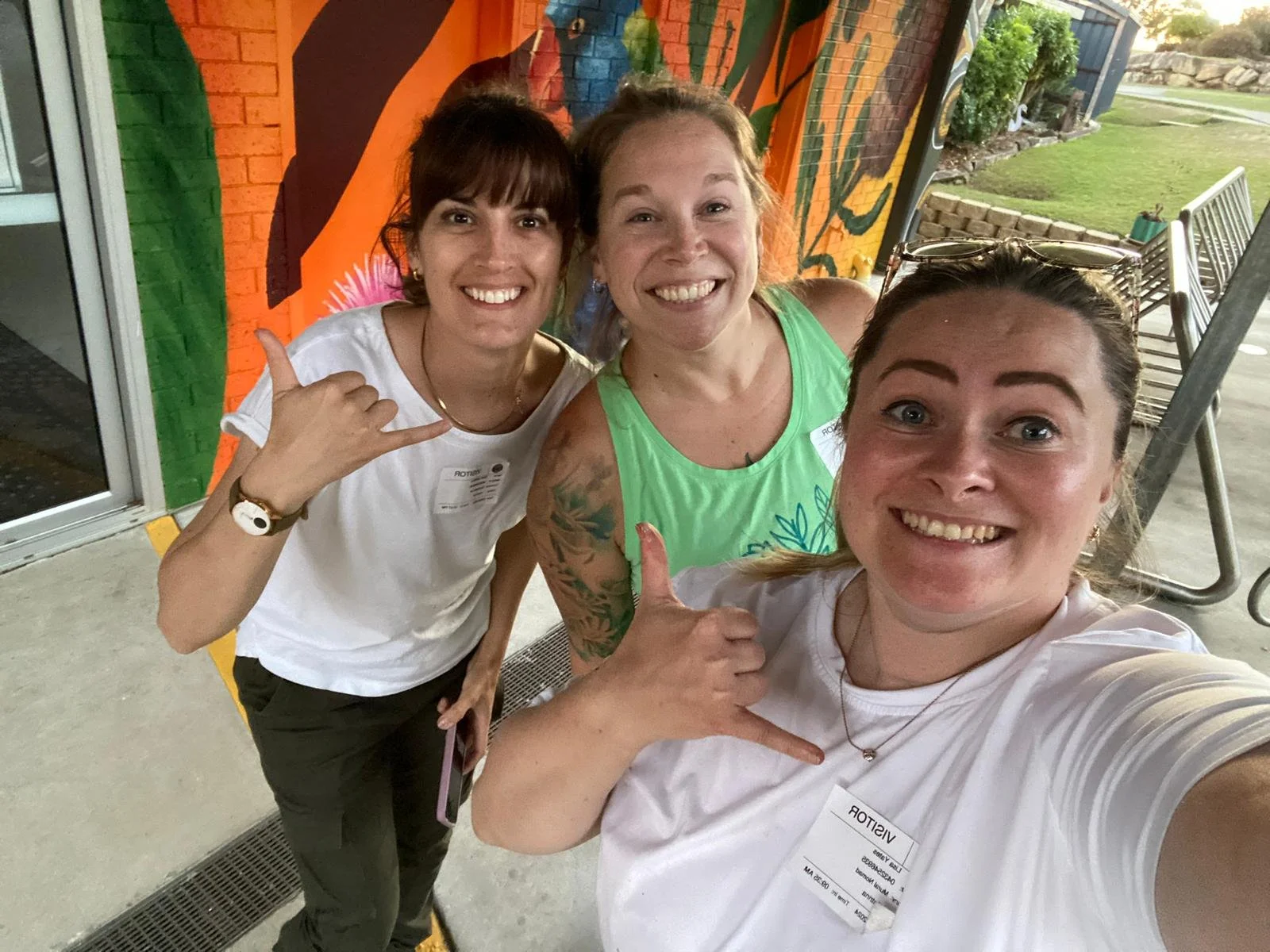 three female artists posing for a photo in Australia in front of a colourful parrot mural