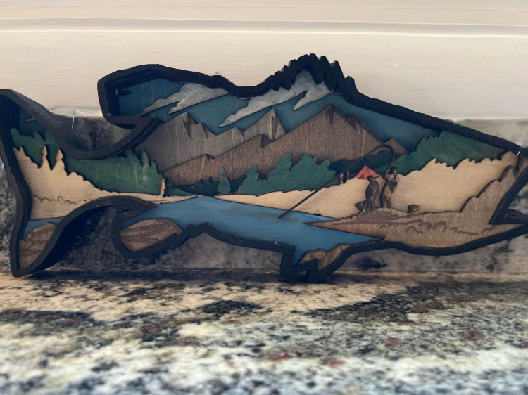 Multiple layered wooden fish painted with a layered fishing scene built it