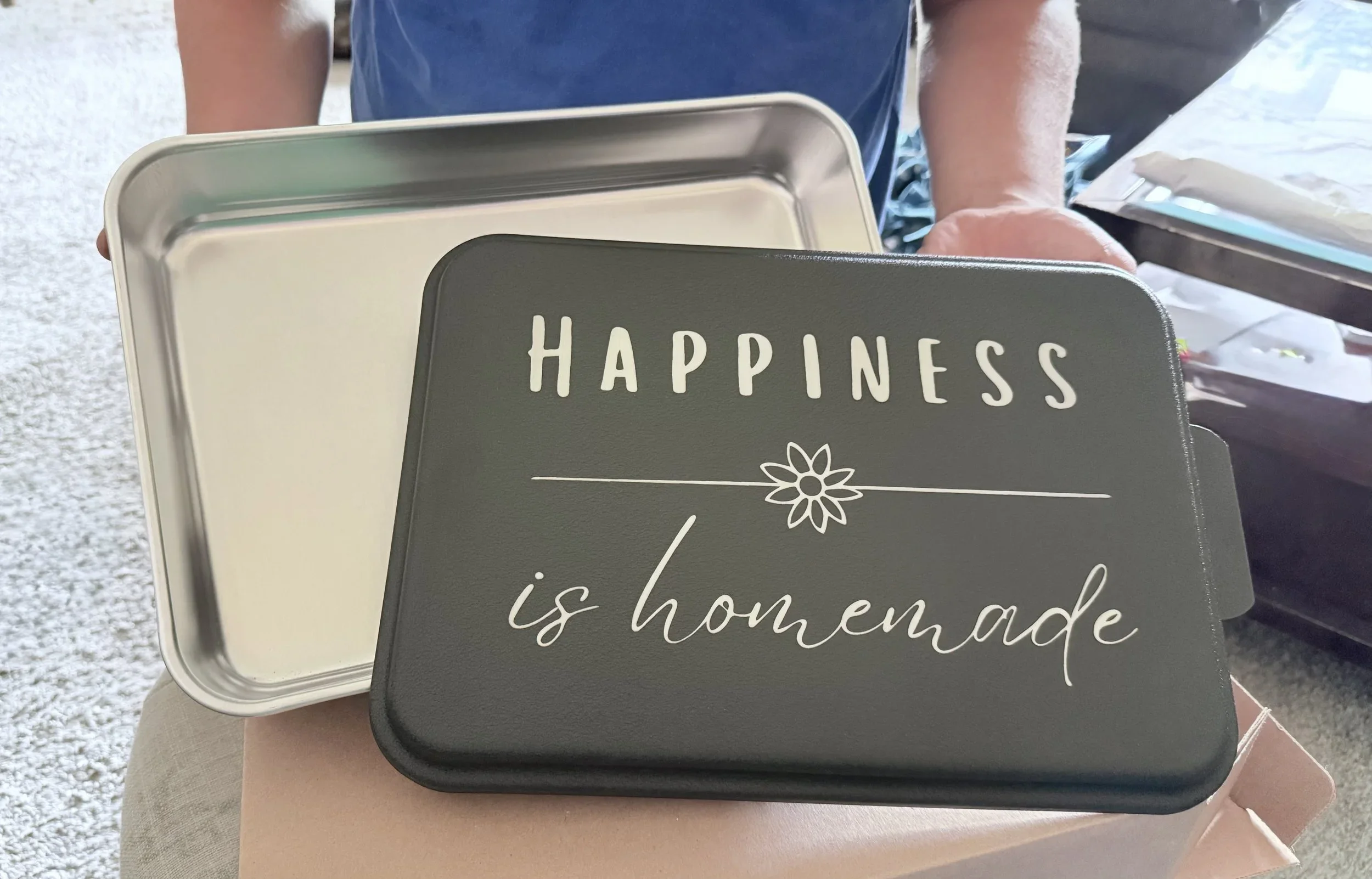 Image of someone holding the cake pan with the words "Happiness is homemade" engraved on it.