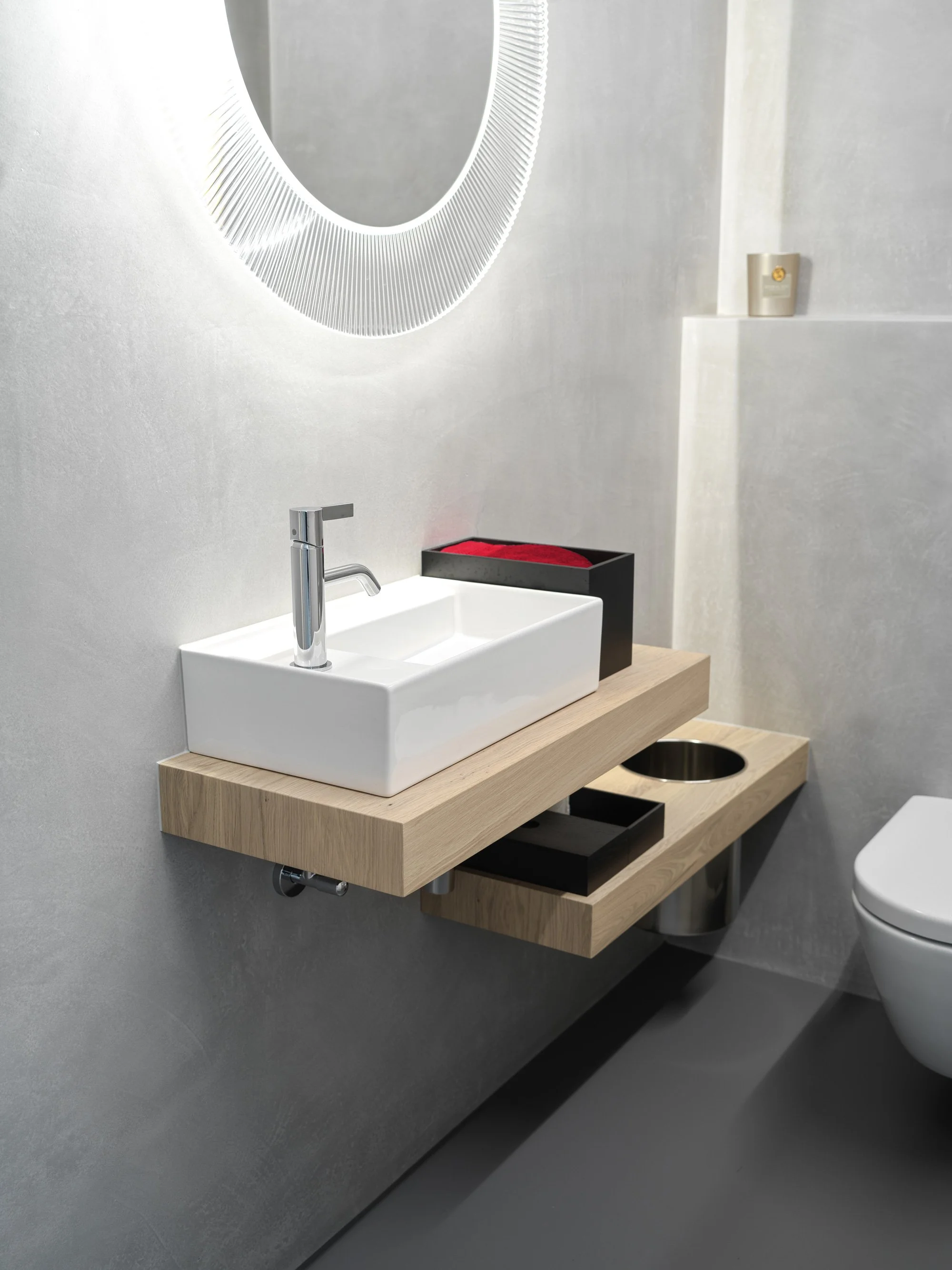 Moderner Badezimmerwaschbecken mit Holzarmatur, runder Spiegel und schwarzen Ablagen