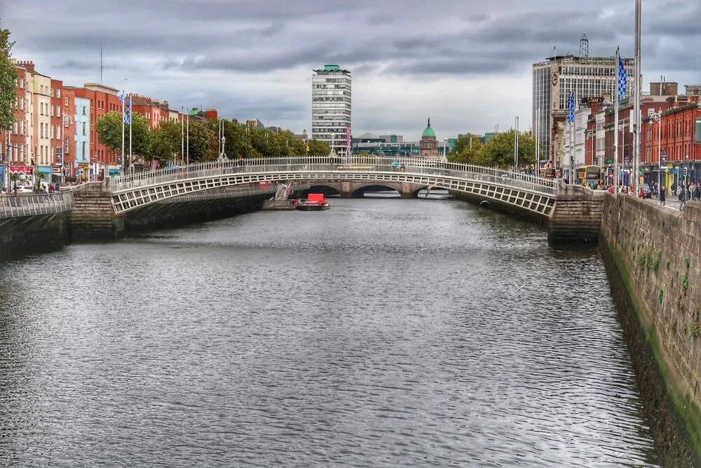 Cross the Liffey River on the iconic white Ha'penny Bridge in Dublin ...