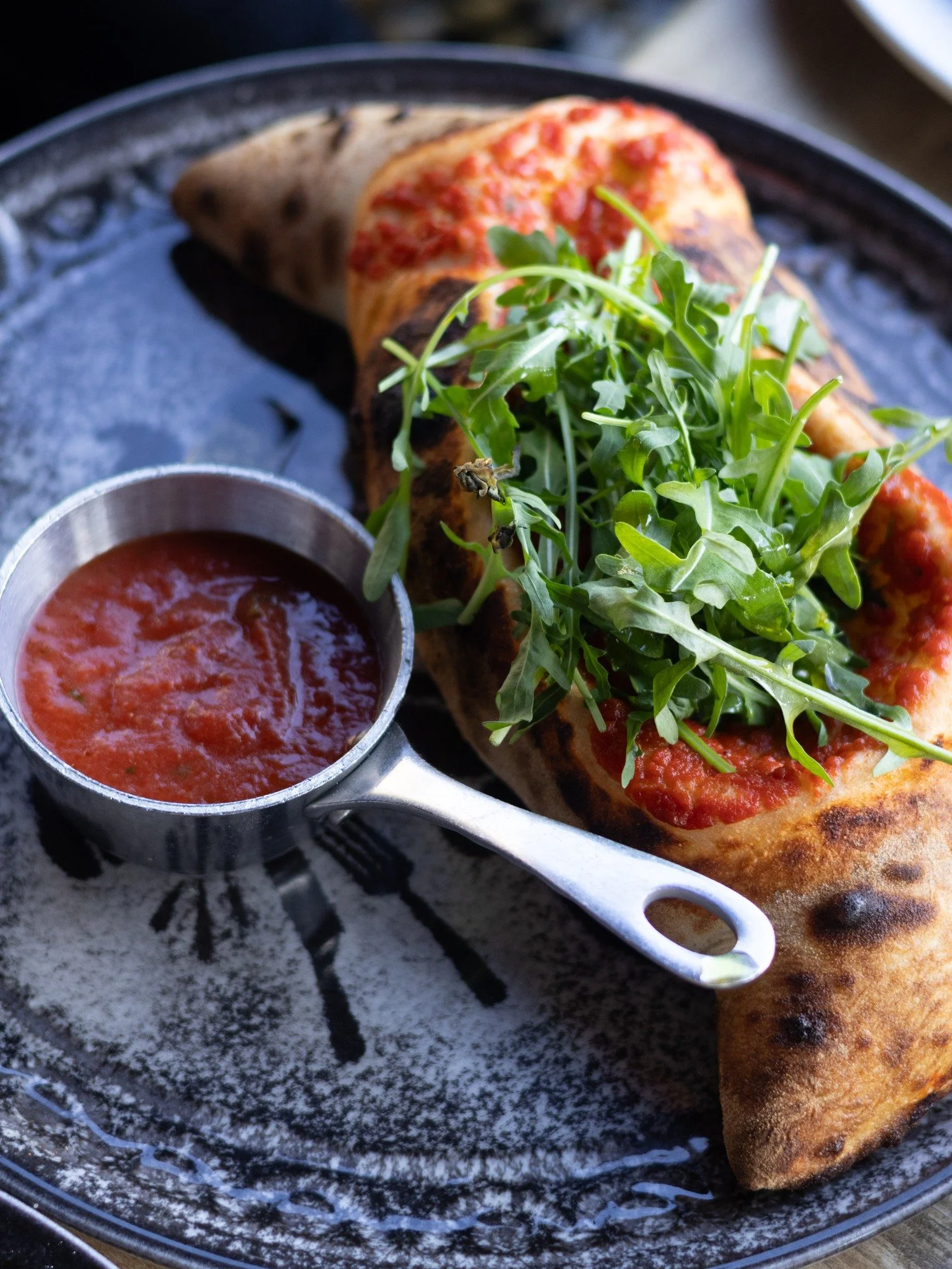En calzone lavet med spr&oslash;d bund, friske r&aring;varer og serveret med hjemmelavet tomatsauce ved siden af. 🍕

En klassiker, mange vender tilbage til igen og igen.