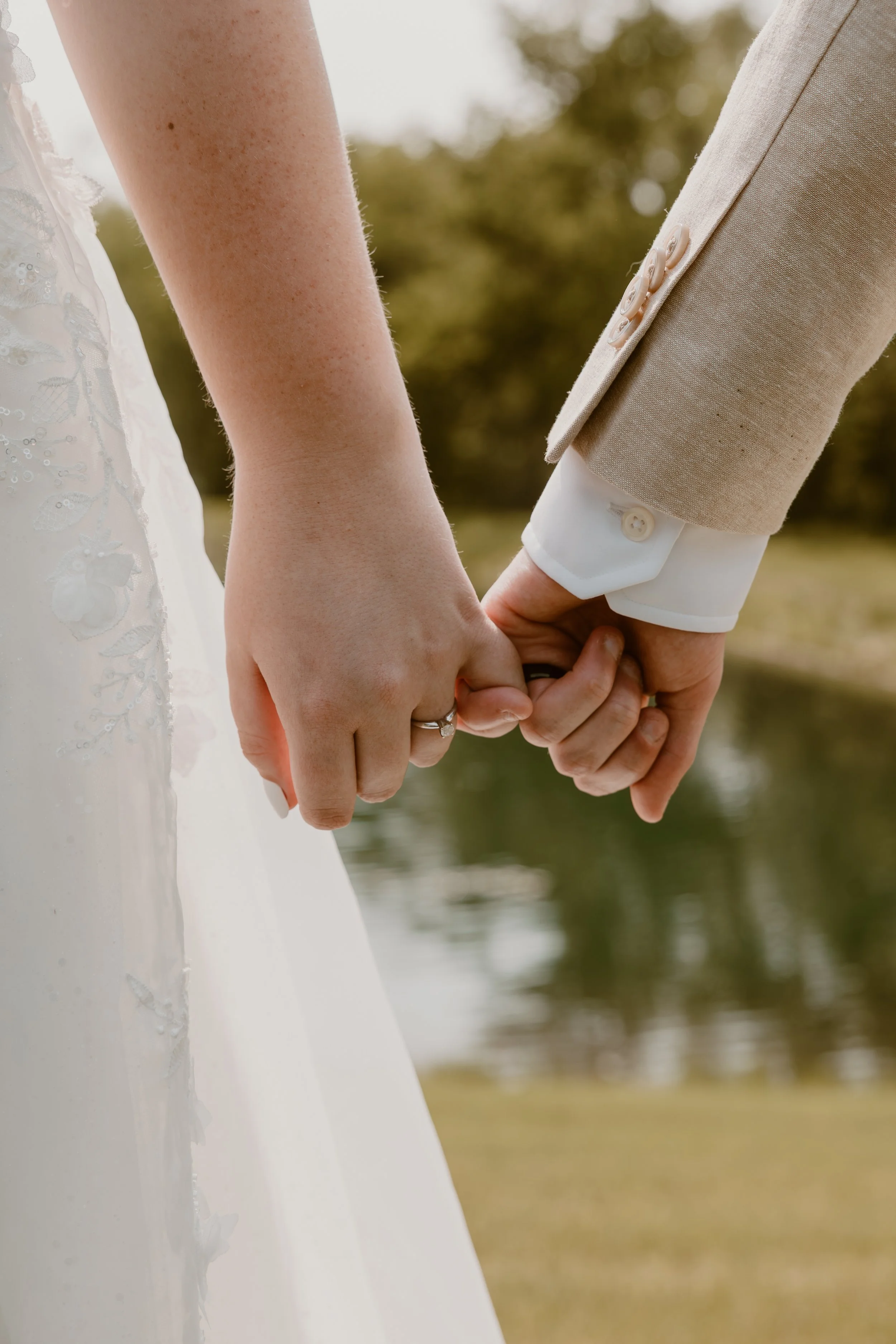 Couple holding hands overlooking the pond at a scenic Des Moines event venue near Altoona, Ankeny, and Pleasant Hill. A peaceful outdoor setting perfect for romantic weddings and unforgettable celebrations in Central Iowa.