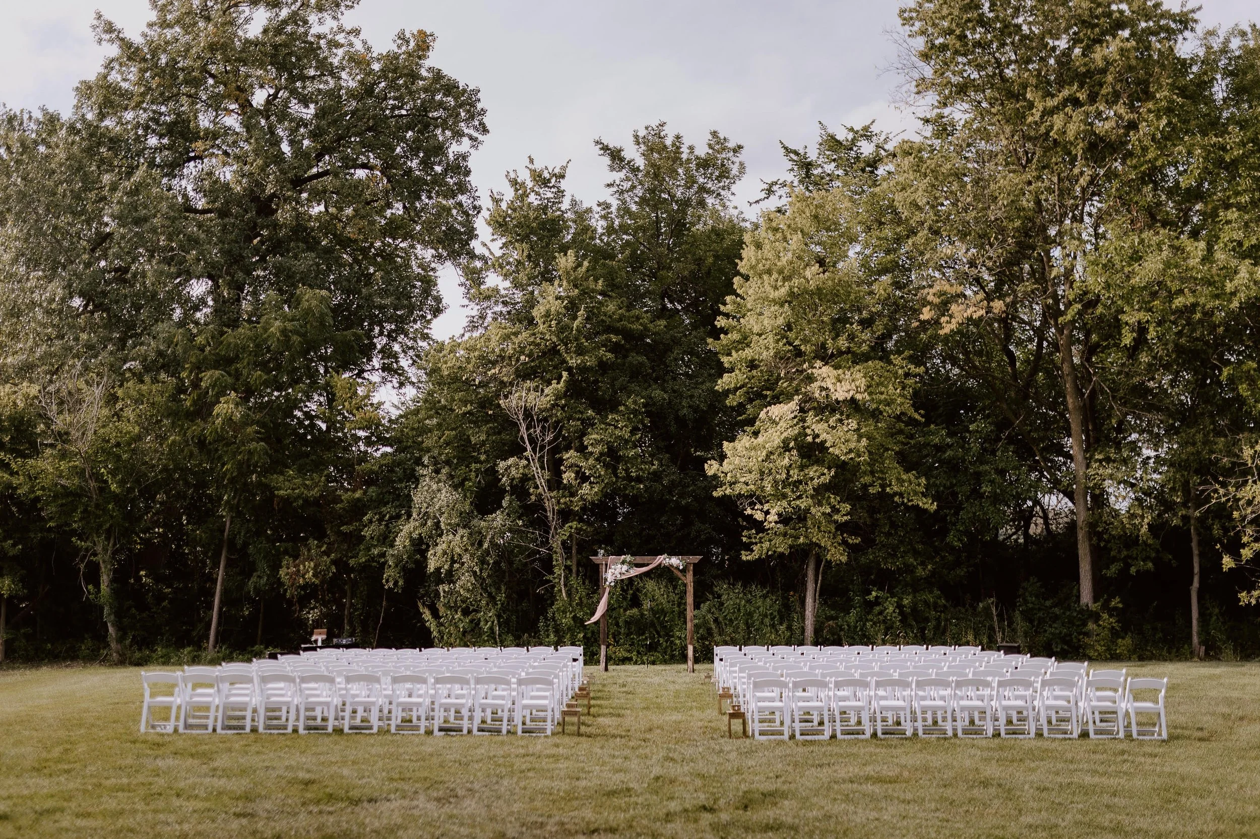 Beautiful wedding setup nestled in front of lush trees in Des Moines near Altoona and Pleasent Hill, creating a serene and romantic outdoor ceremony space. A perfect setting for couples looking for a natural, elegant backdrop on their special day.
