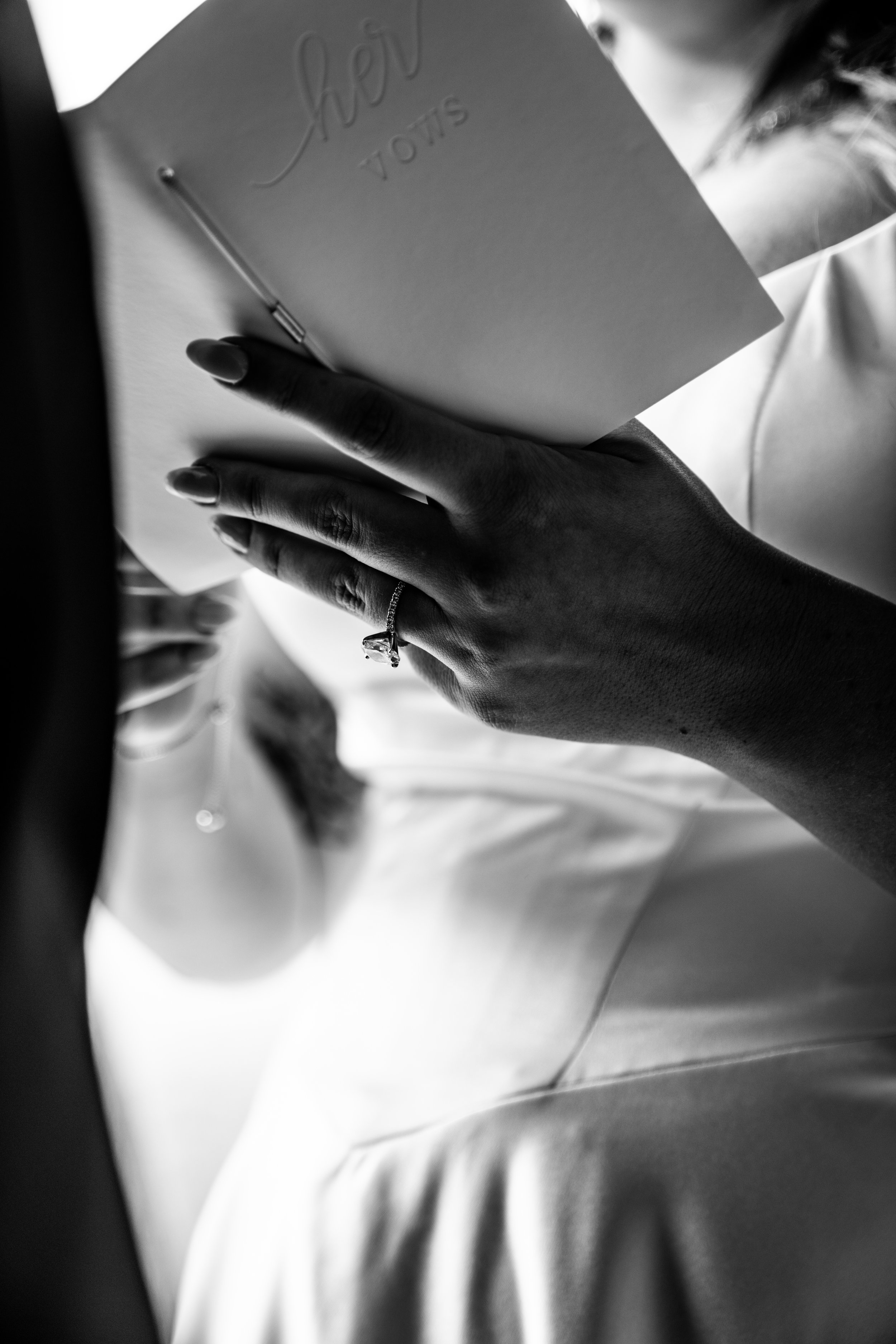 Bride reading her handwritten wedding vows, featuring a close-up of her engagement ring and dress—captured at Northbridge Event Center in Central Iowa during an intimate wedding moment.