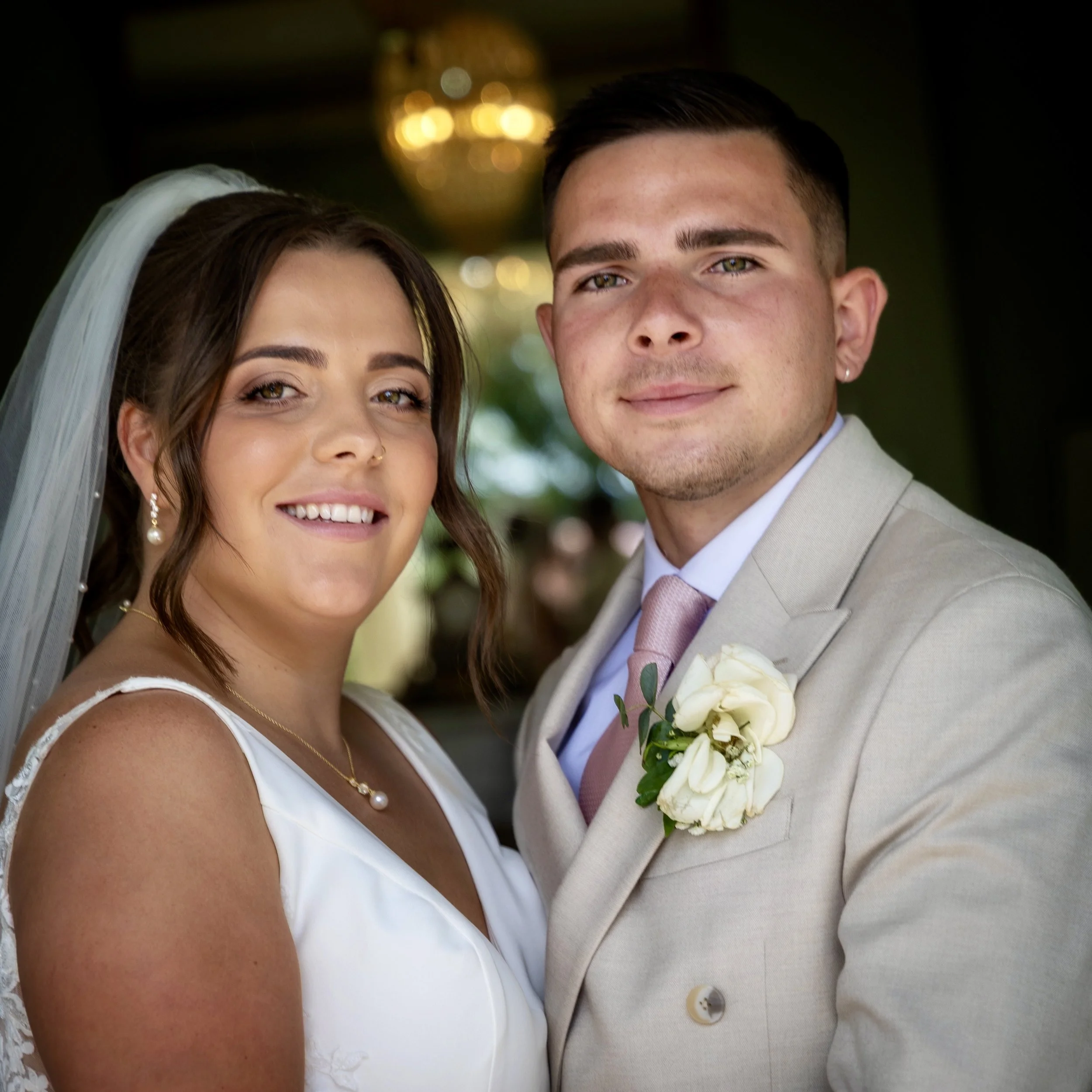 A bride and groom smiling at the camera during their wedding celebration.