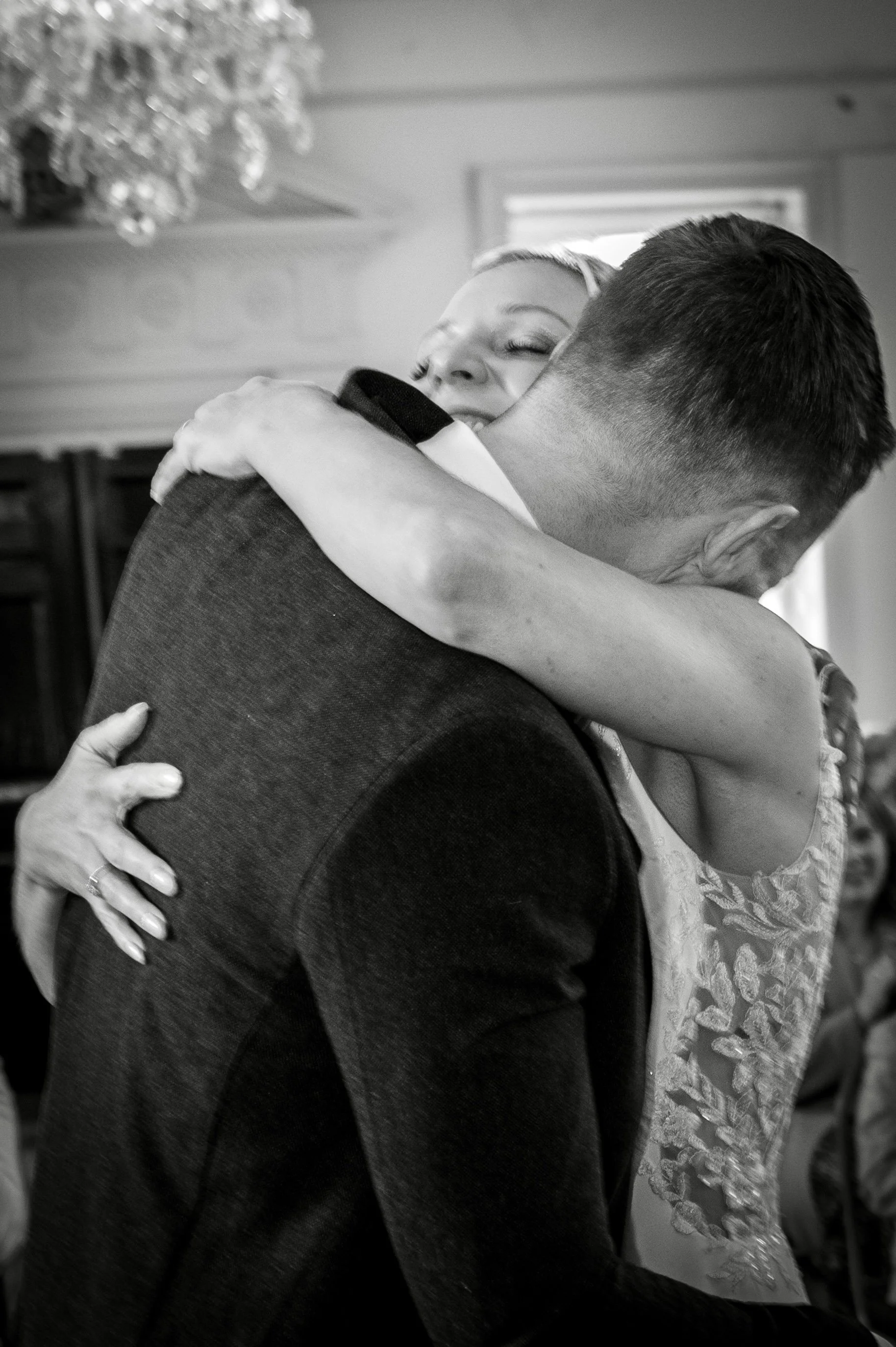 A black and white photo of two people embracing and hugging each other tightly.