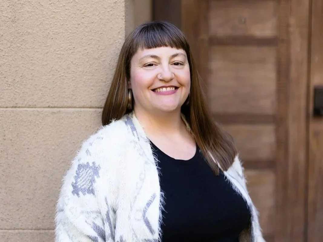 michelle puckett social justice coach with long brown hair wearing black top and white and grey fluffy cardigan