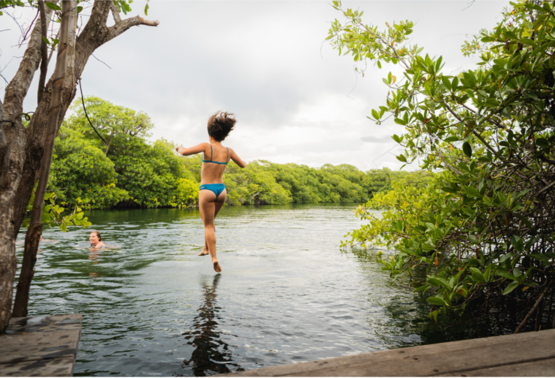 A girl is enjoying jumping in the running water in Tulum.