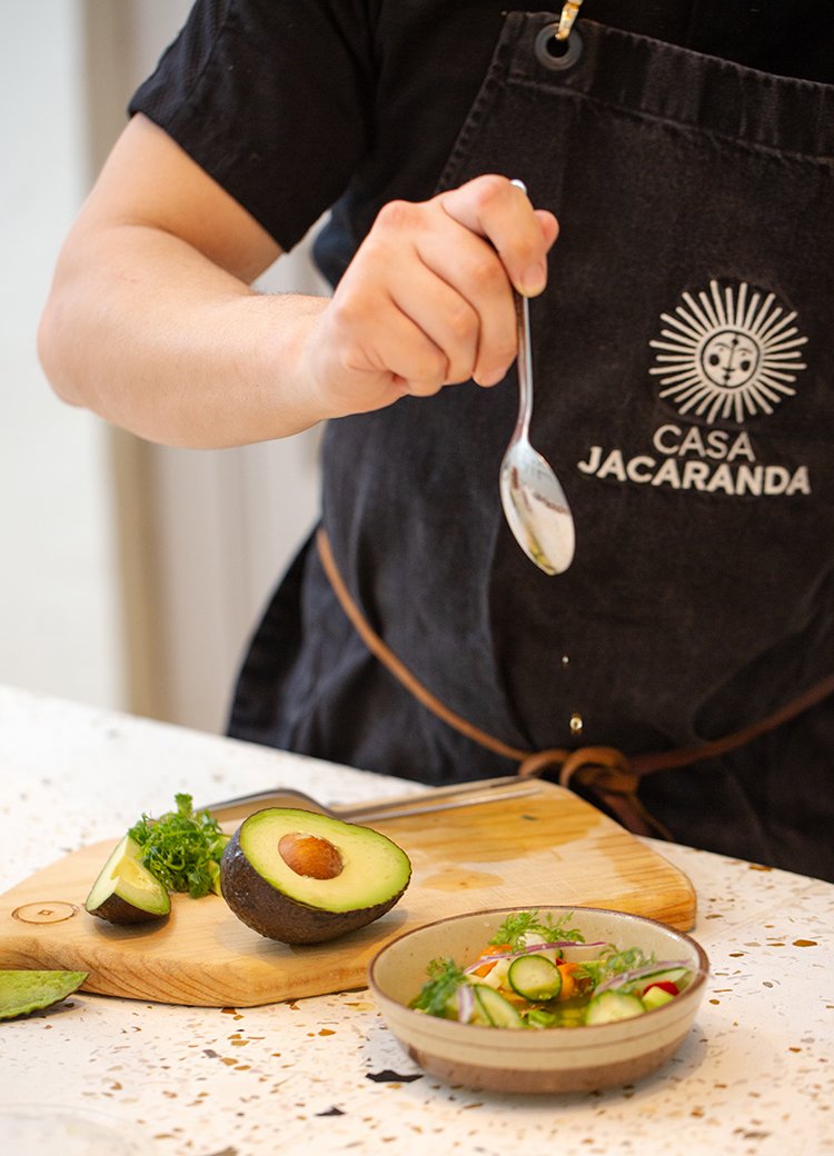 Hands spoon avocados at Casa Jacaranda's cooking class