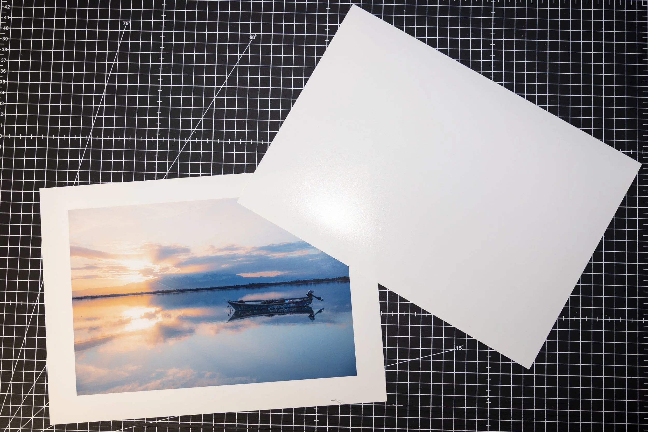 Photo d'une rivière au coucher du soleil avec un bateau à moteur en bois, reflétant le ciel coloré dans l'eau calme, avec un paysage de montagnes au fond.