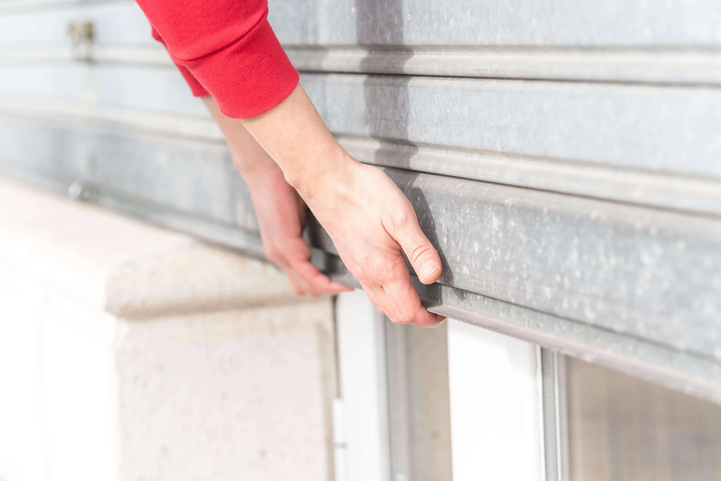 Person using their hands to manually open a broken garage door.