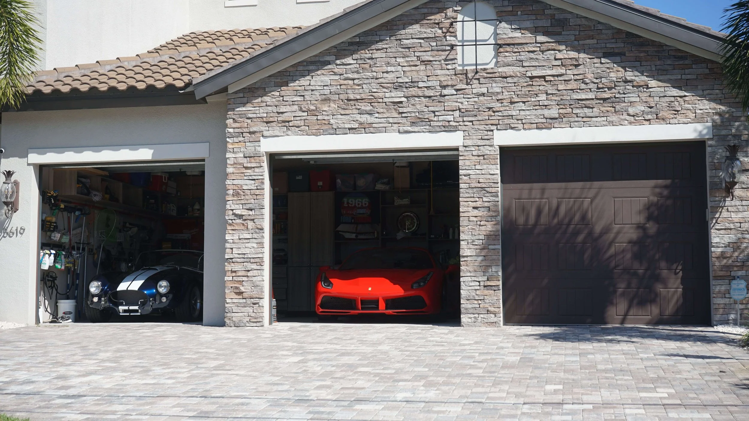 3-car garage with 2 doors open revealing valuable sports cars.