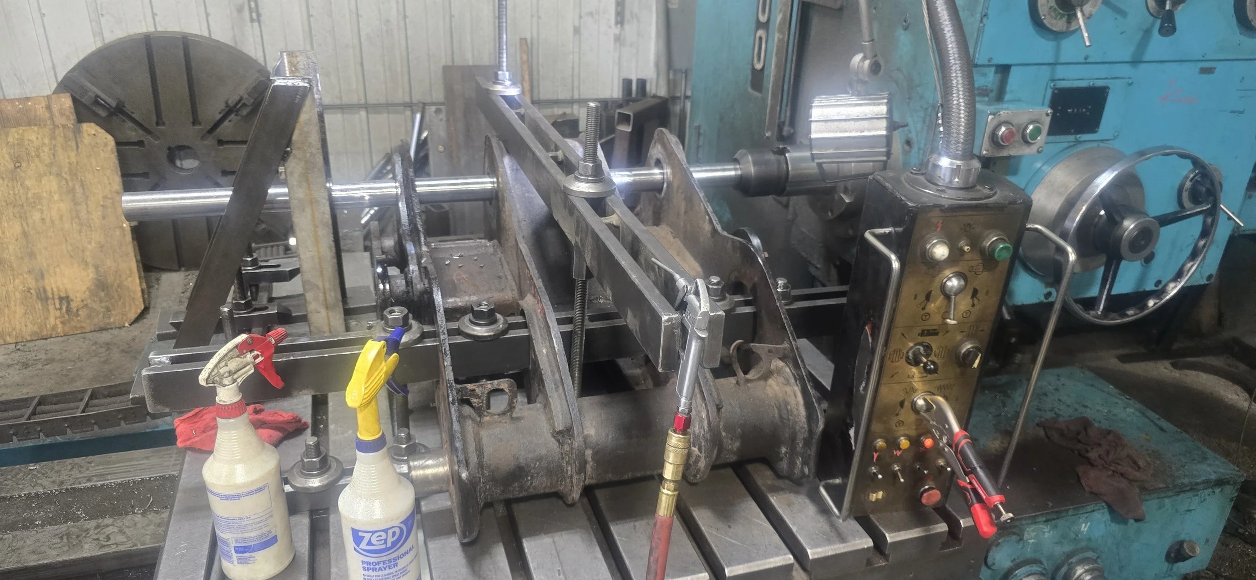 A metal lathe machine with tools and spray bottles on the worktable, used for machining metal parts.