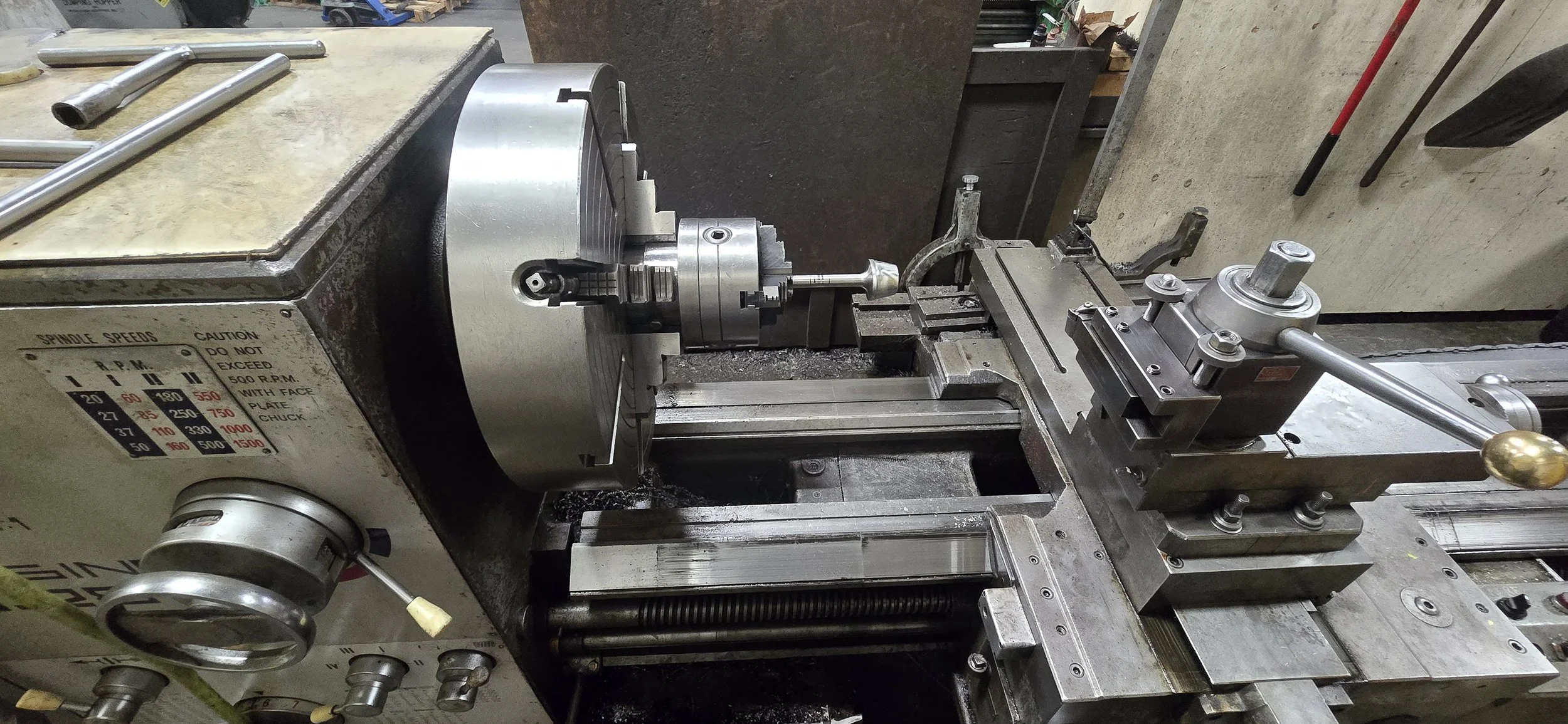 A metal lathe machine used for machining metal parts, with various components and controls visible.