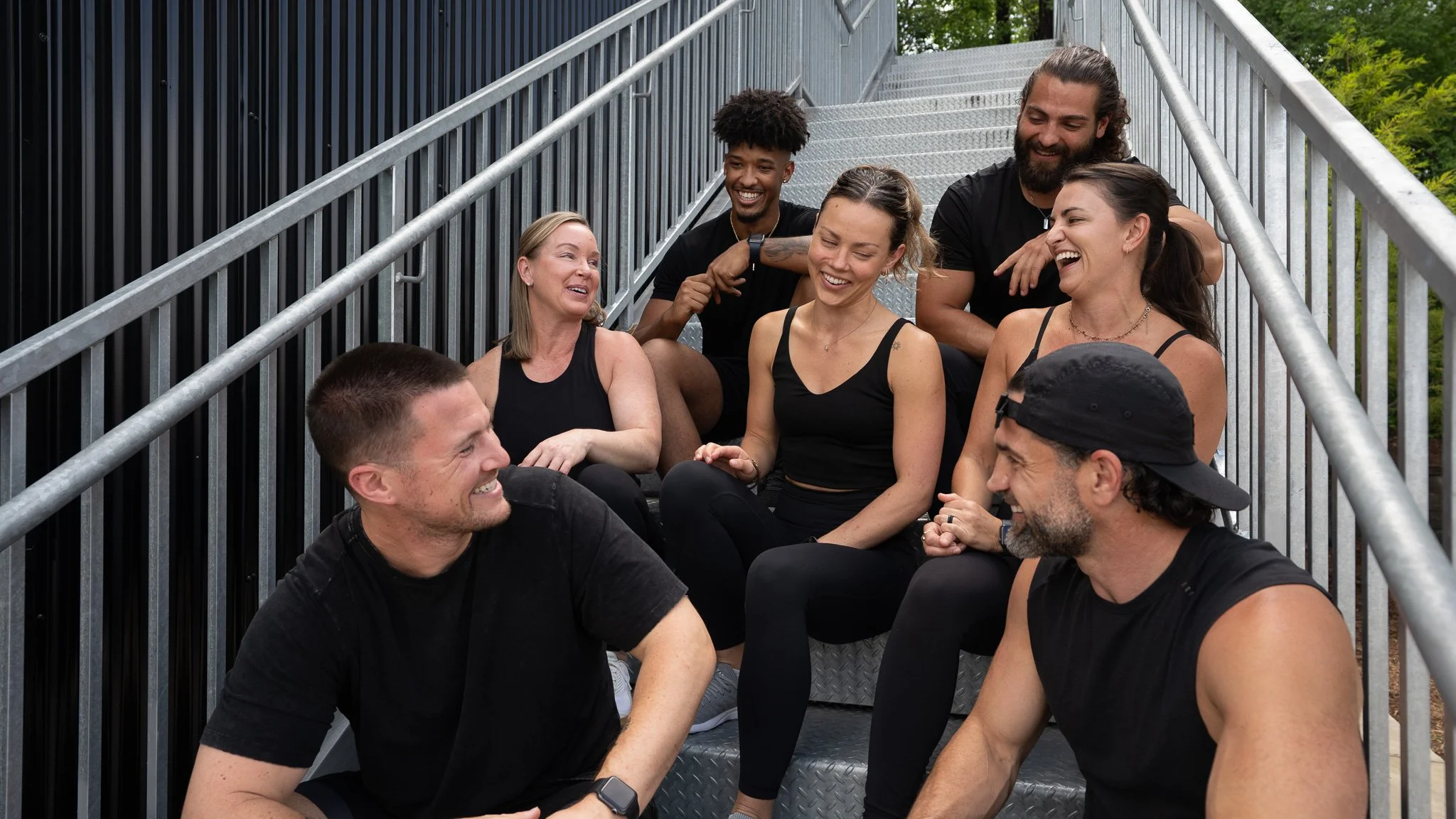 Photo of gym staff smiling and sitting on stairs 
