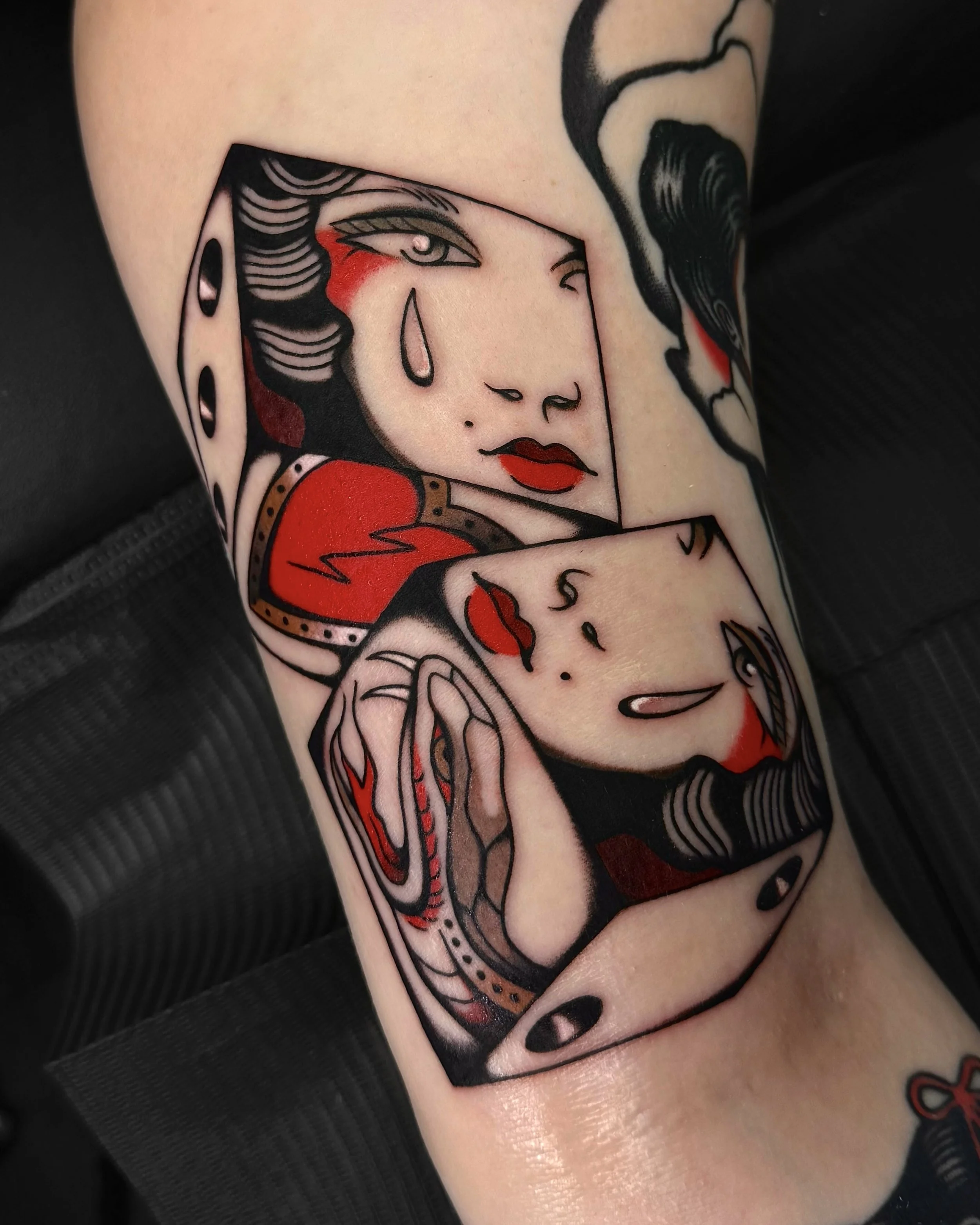 Tattoo of a stylized woman with tears, red lips, and dark hair, surrounded by a dice and other abstract elements.