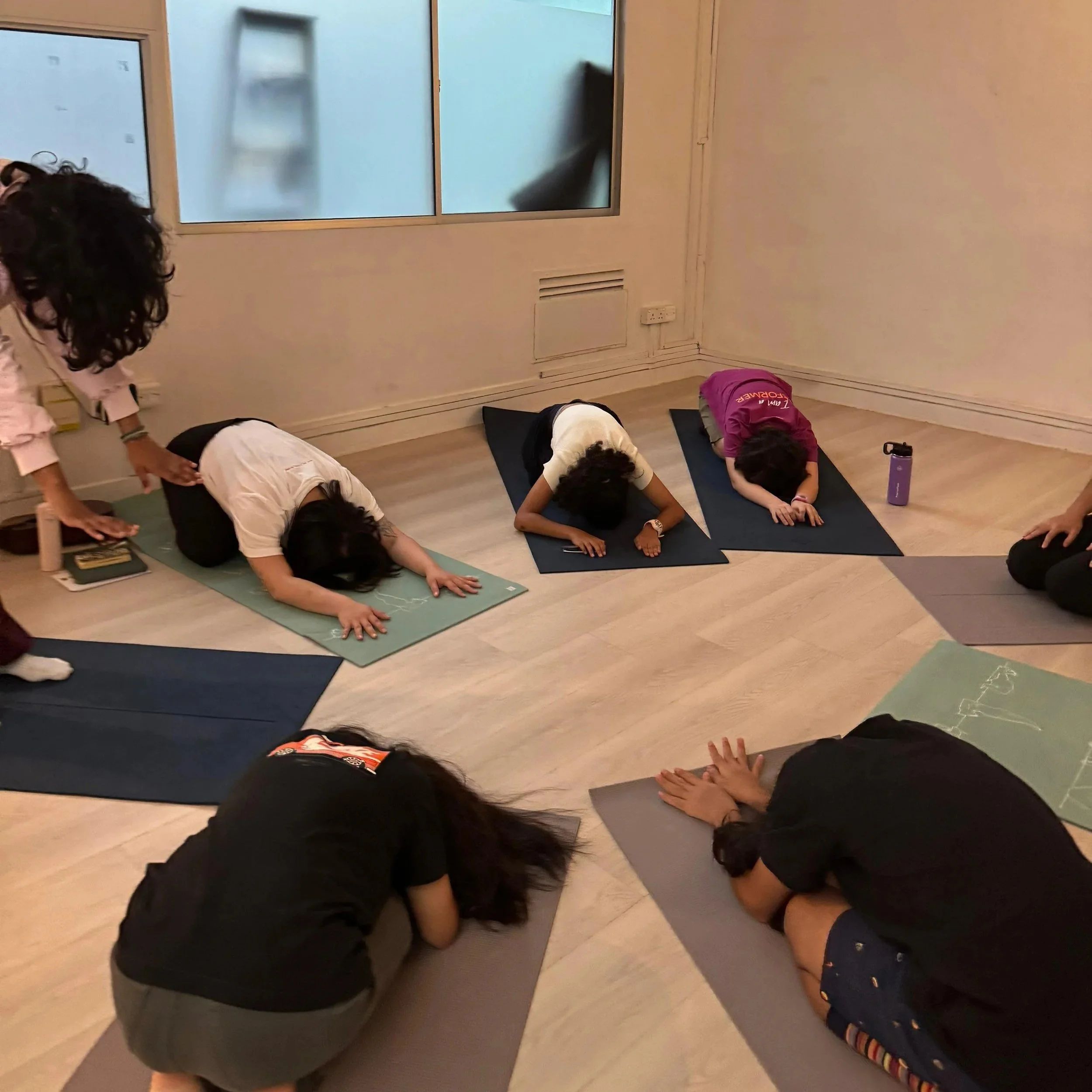 People practicing yoga in a room, performing downward dog pose on mats.