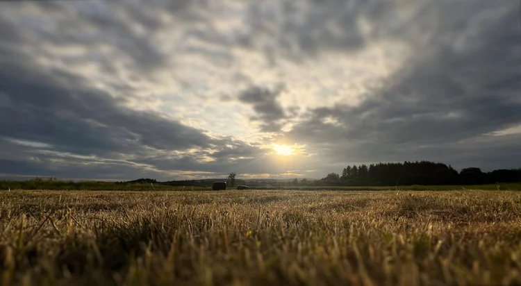 A stubble field at dusk under a broken sky