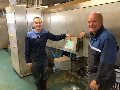 Two of the Smith family of Barneighthill Farm beside the control screen of their milking robot