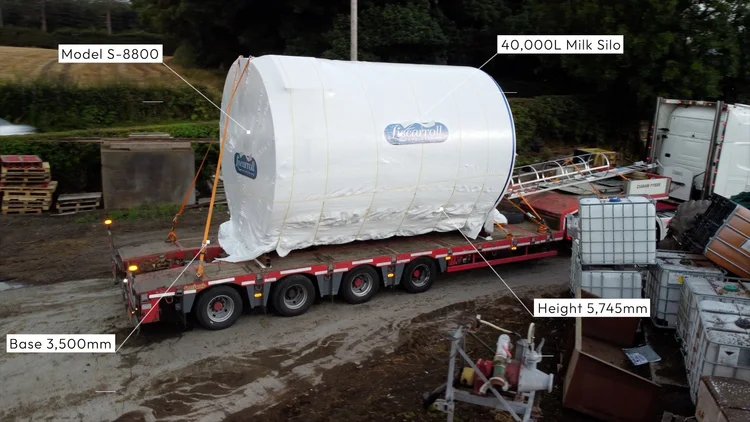 A 40,000 litre Liscarroll milk silo, wrapped in white for transport, lying on a low-loader trailer in a farm yard, with the model S-8800, 3,500mm base and 5,745mm height marked on the frame