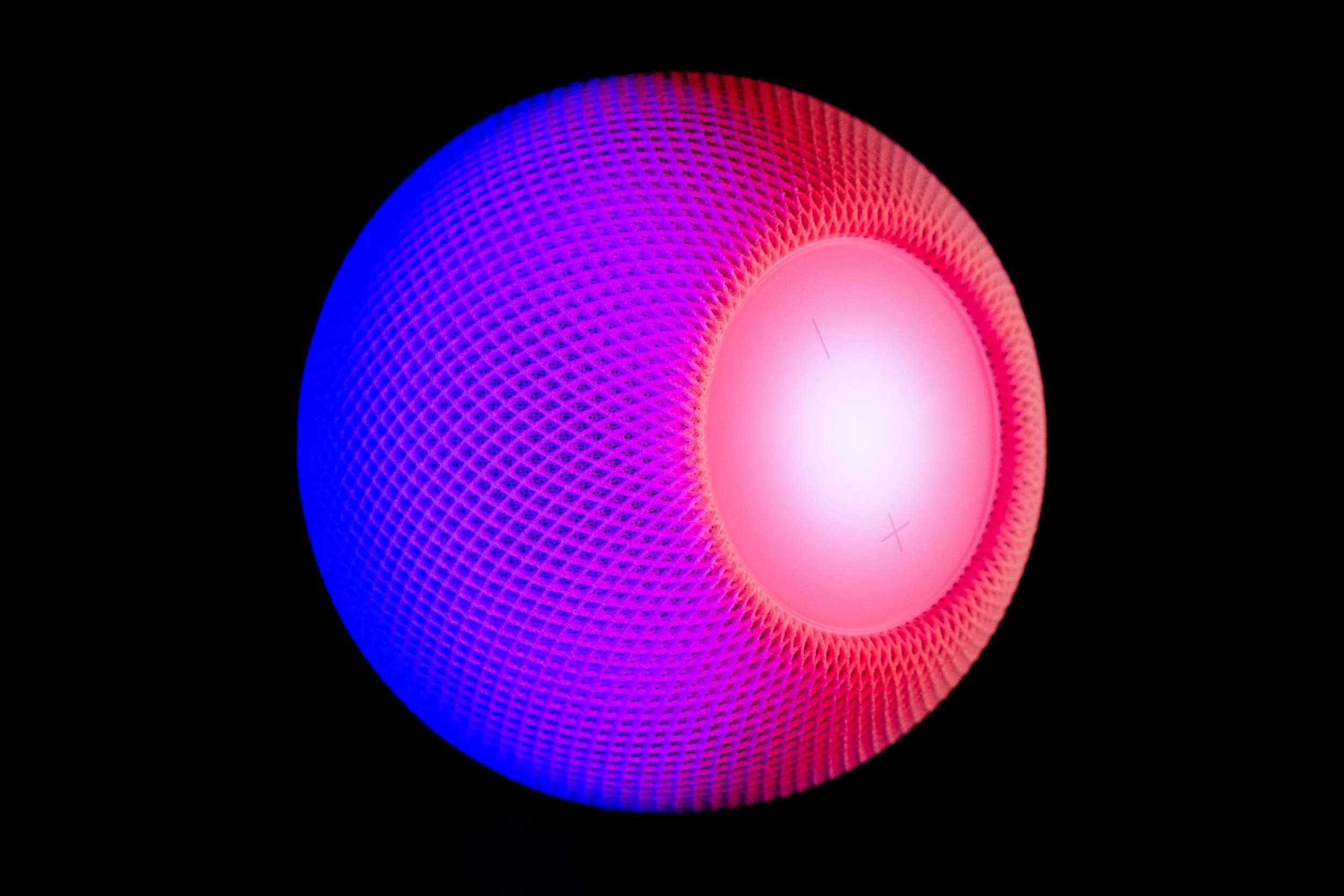 Close-up of a spherical smart speaker with pink and blue LED lights against a black background.