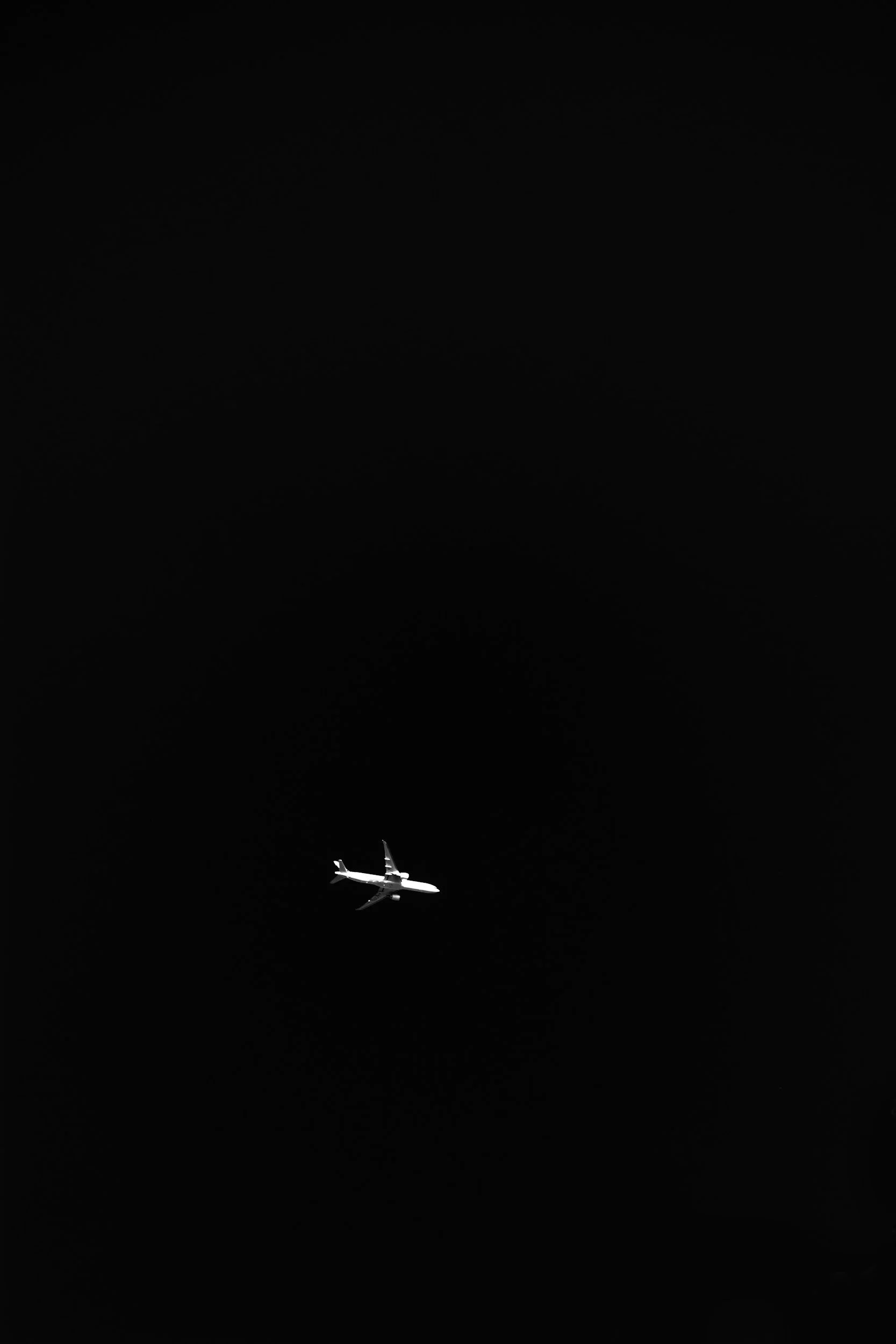 A white airplane flying in dark night sky.
