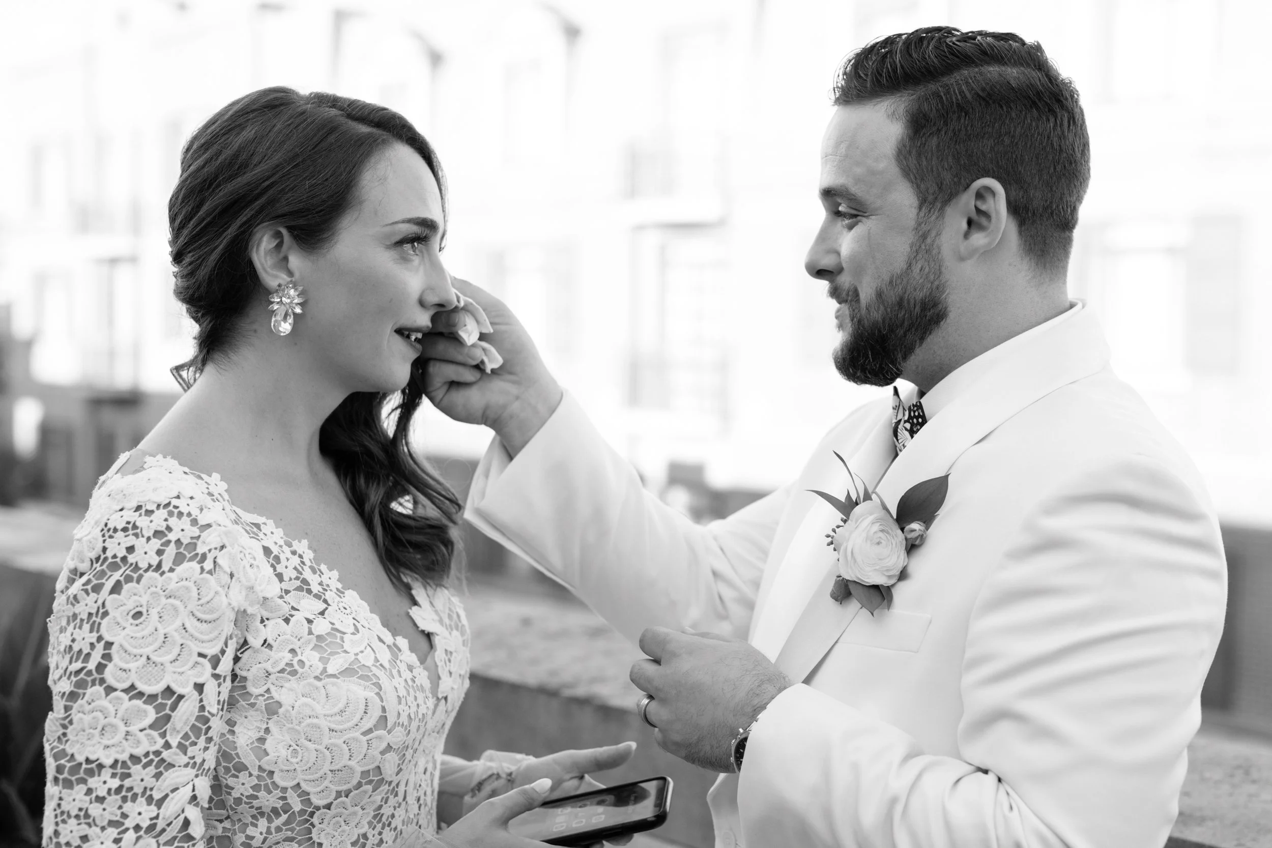 Downtown Charleston wedding. A black and white image of groom wiping bride's tears during their vow reading. 