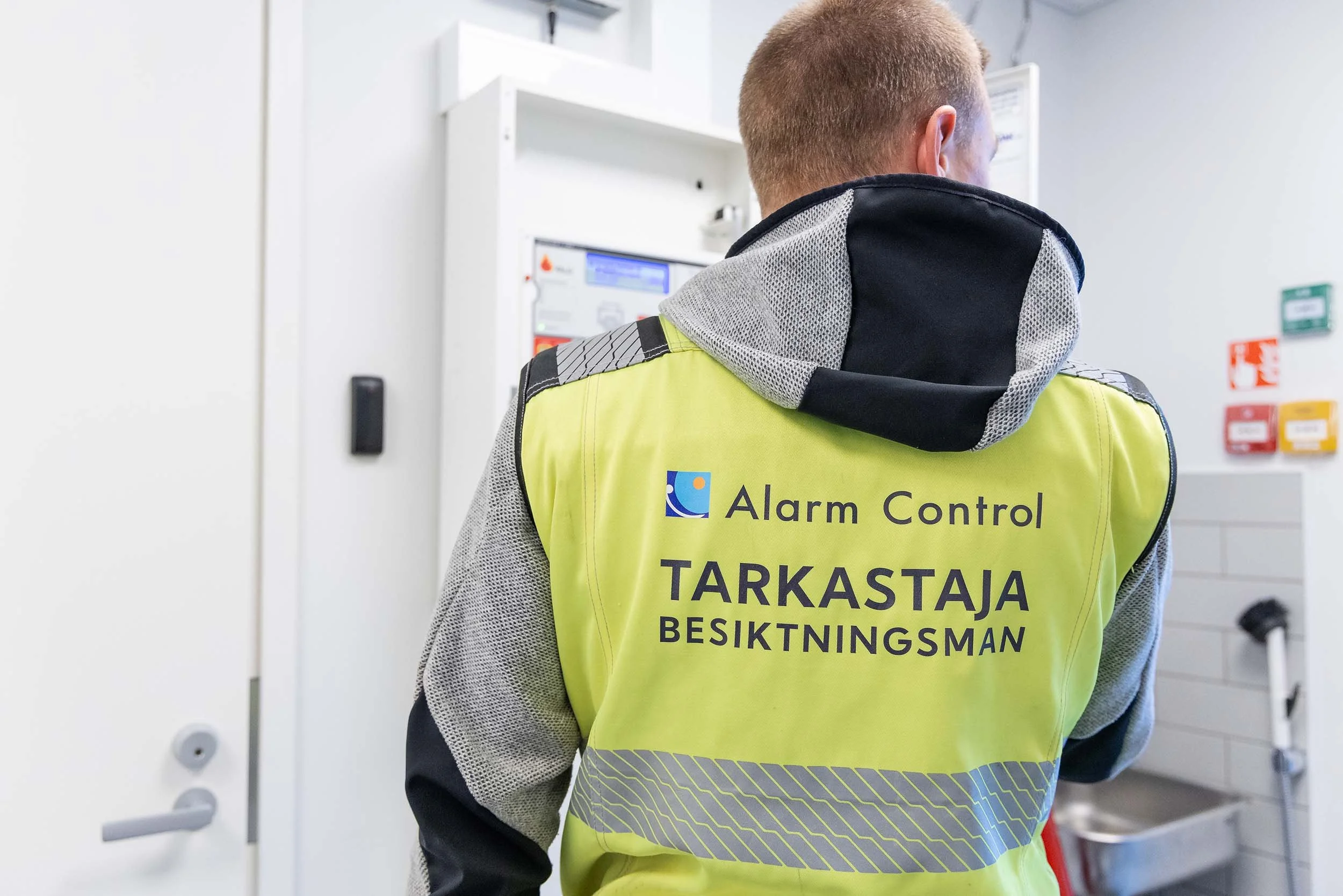 Tarkastaja töissä, liivin selässä lukee Alco Tarkastus, tarkastaja - besiktningsman