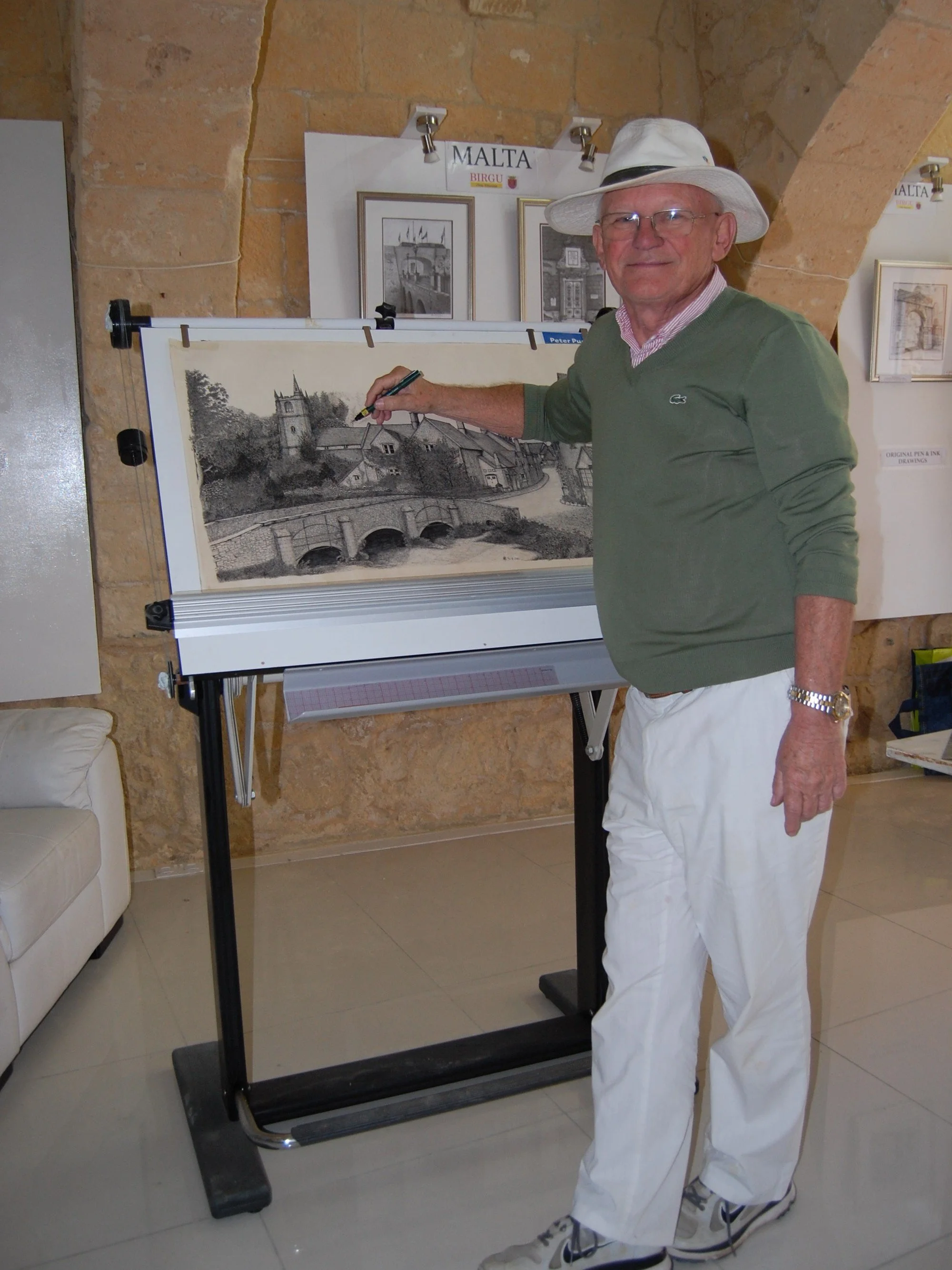 Peter working on his large Castle Combe drawing  in his Malta art gallery.