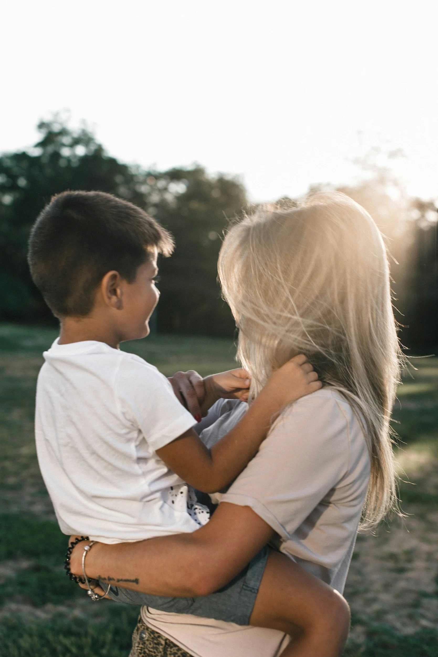 woman hugging child, both looking at sunset