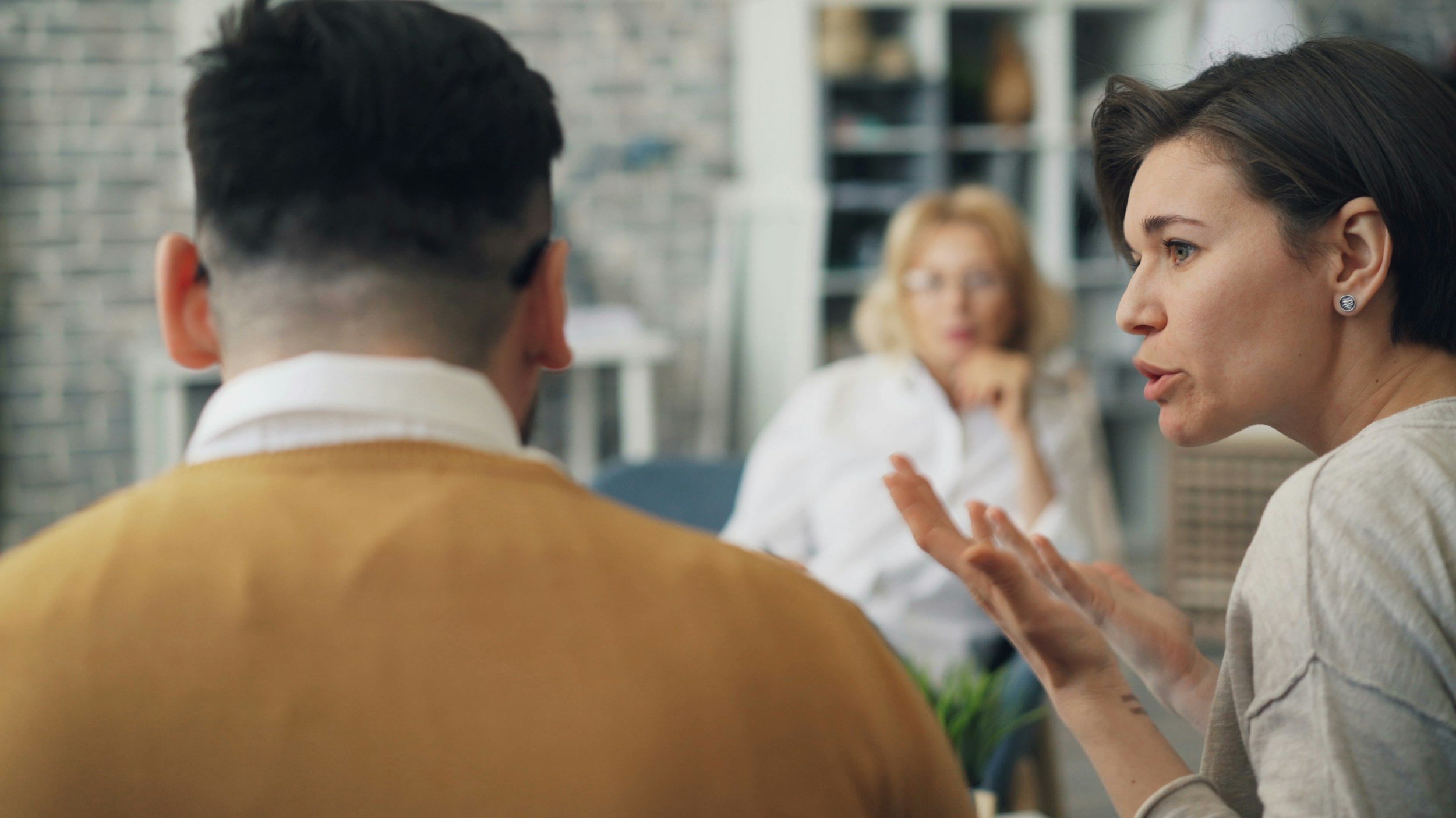 Younger family members discussing seriously with an older family member sitting in the background
