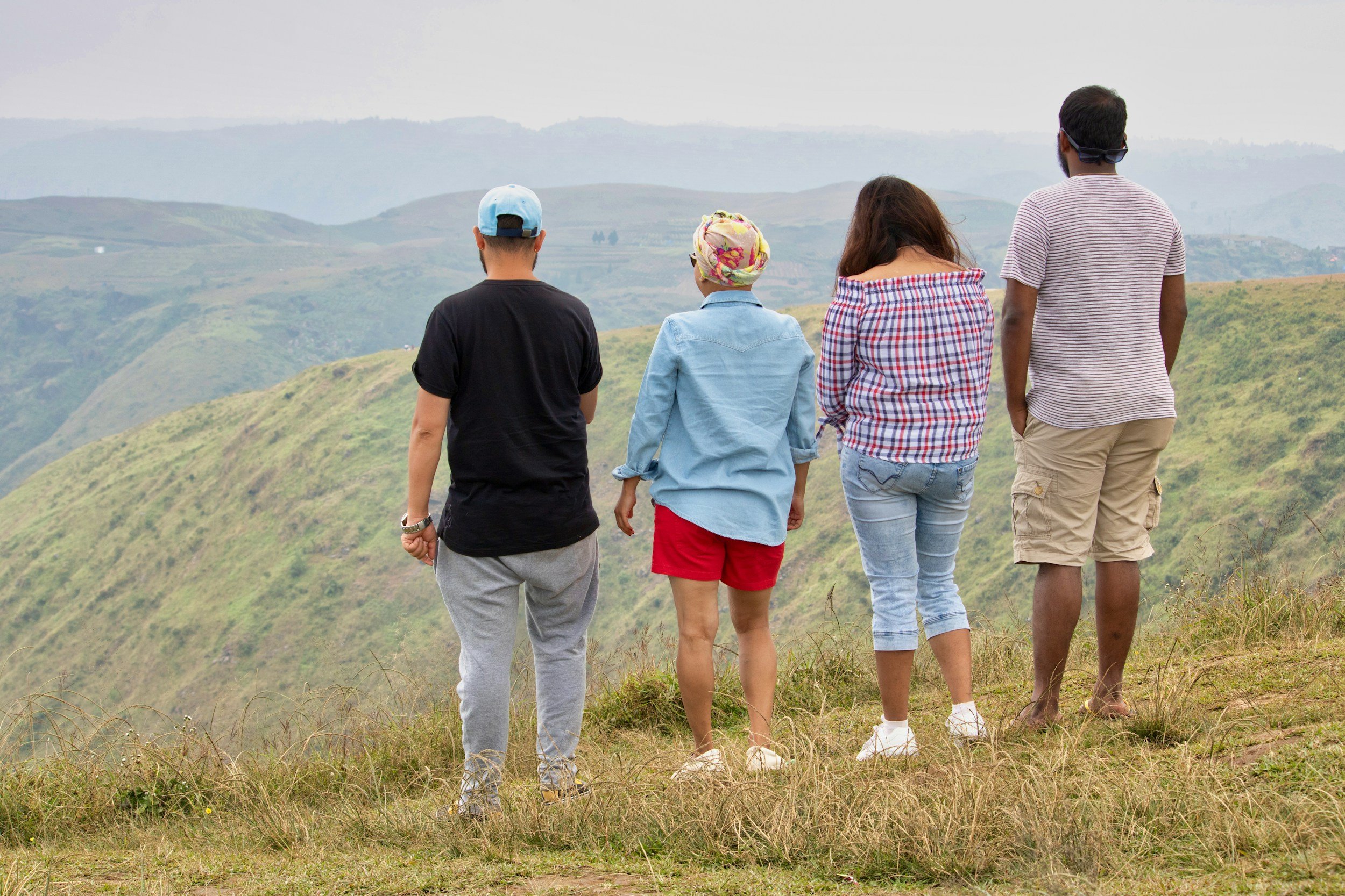 Four people looking over the edge of a rolling mountain. One woman is wearing a heascarf.