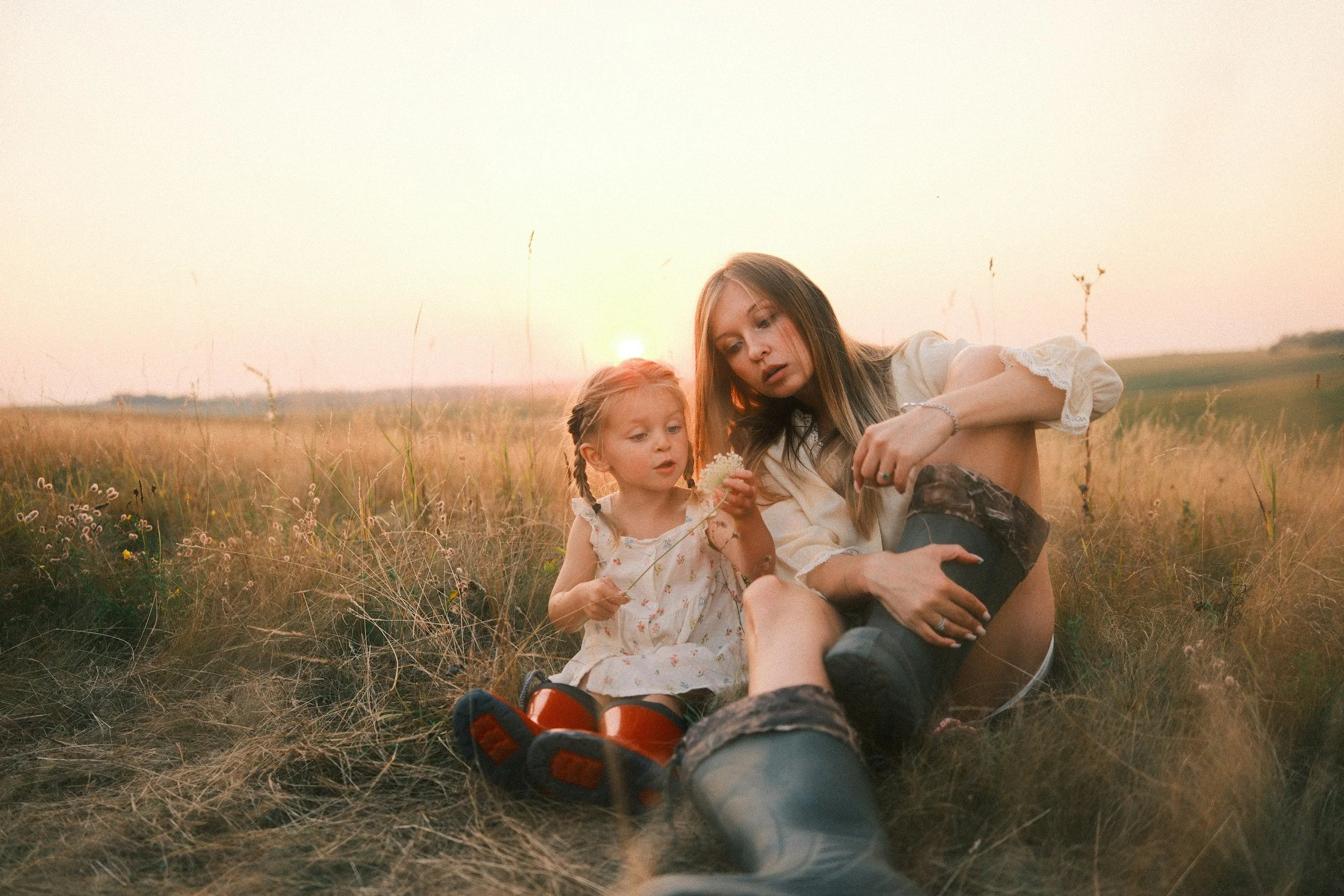 Mother and daughter sitting outside at sunset in a field talking about grief